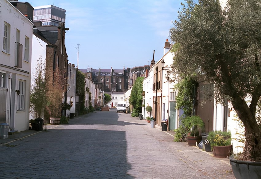 Charming cobbled street in Bathurst Mews in Bayswater with white terraced houses and greenery.