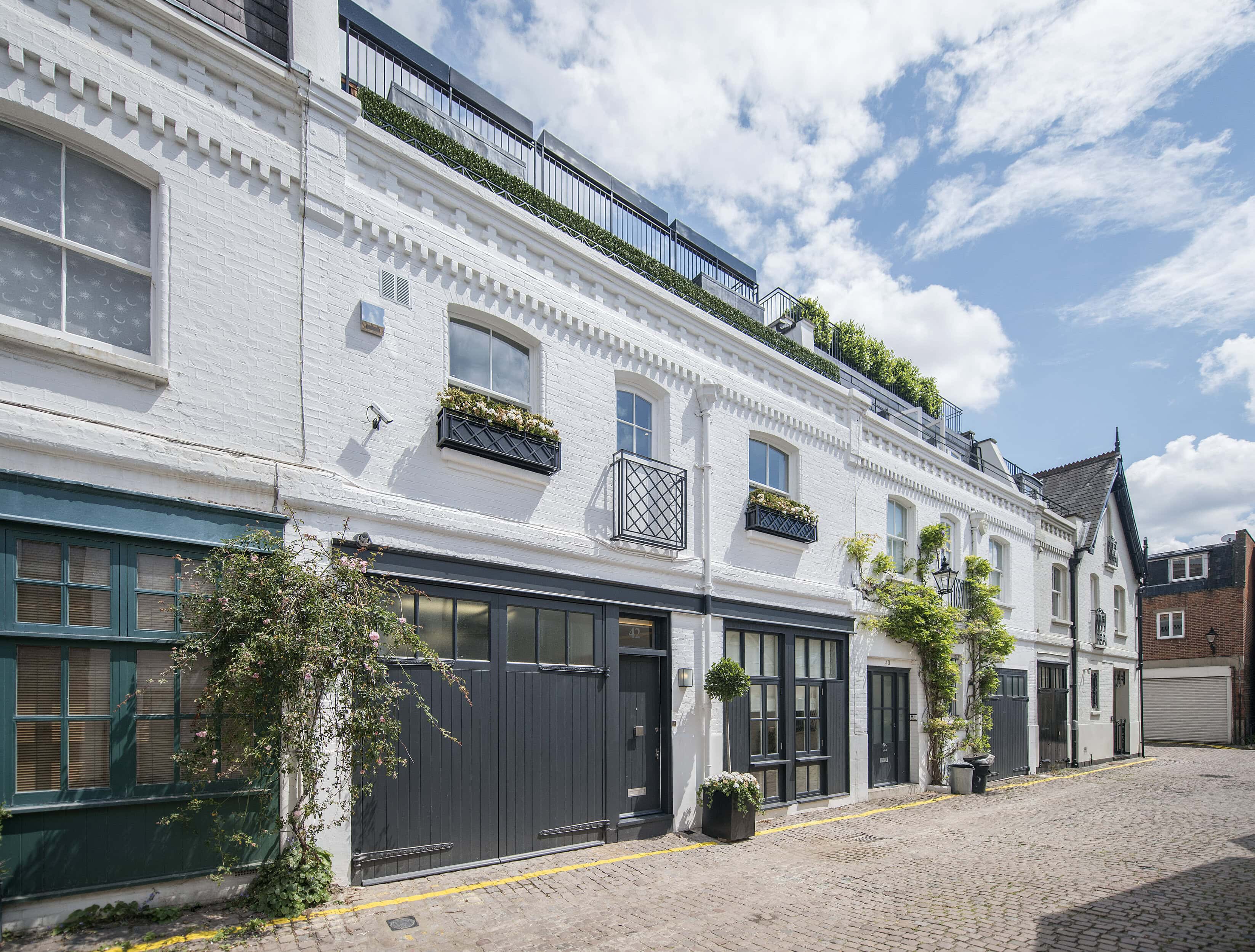 Elegant white townhouse in Adam and Eve Mews, Kensington, with black accents and rooftop terrace.