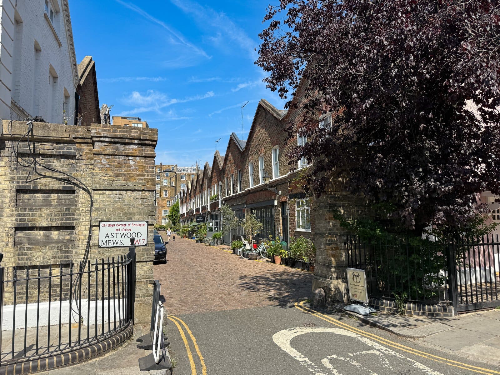 Charming residential street in Kensington with brick row houses and lush trees, typical of London’s historic architecture.