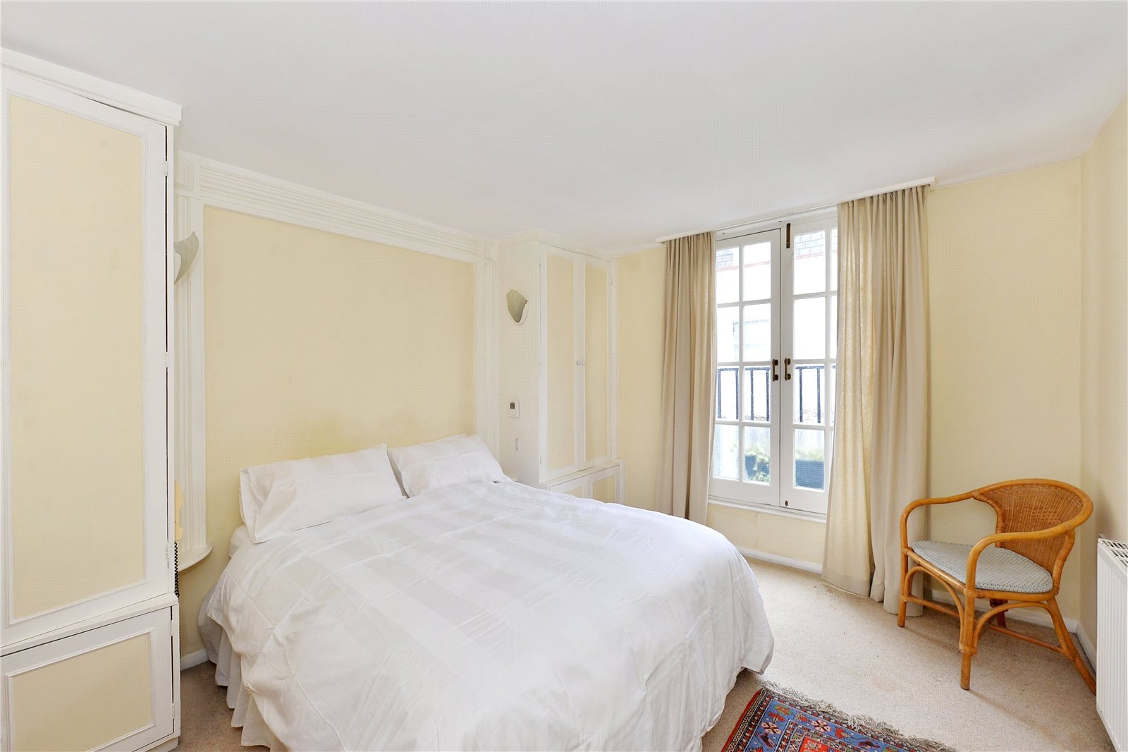 Bright bedroom with large window and cosy decor, perfect for city living in London.