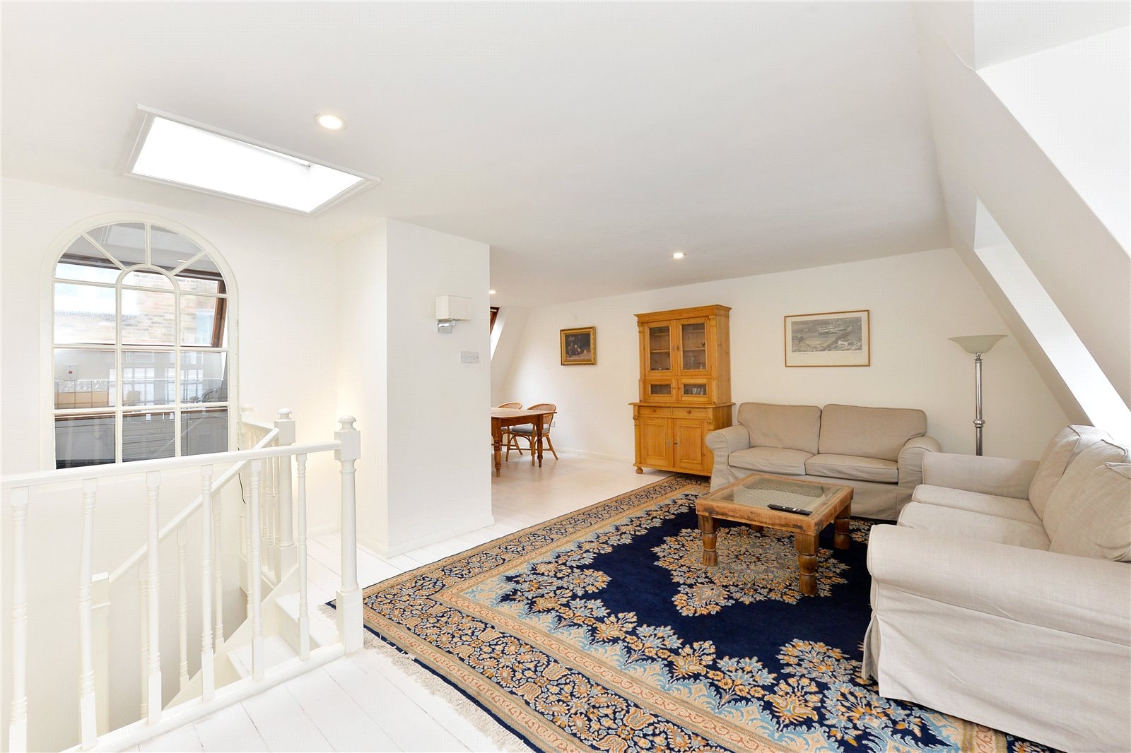 Bright, airy living room with white walls, skylight, and comfortable beige sofas showcasing elegant interior design.