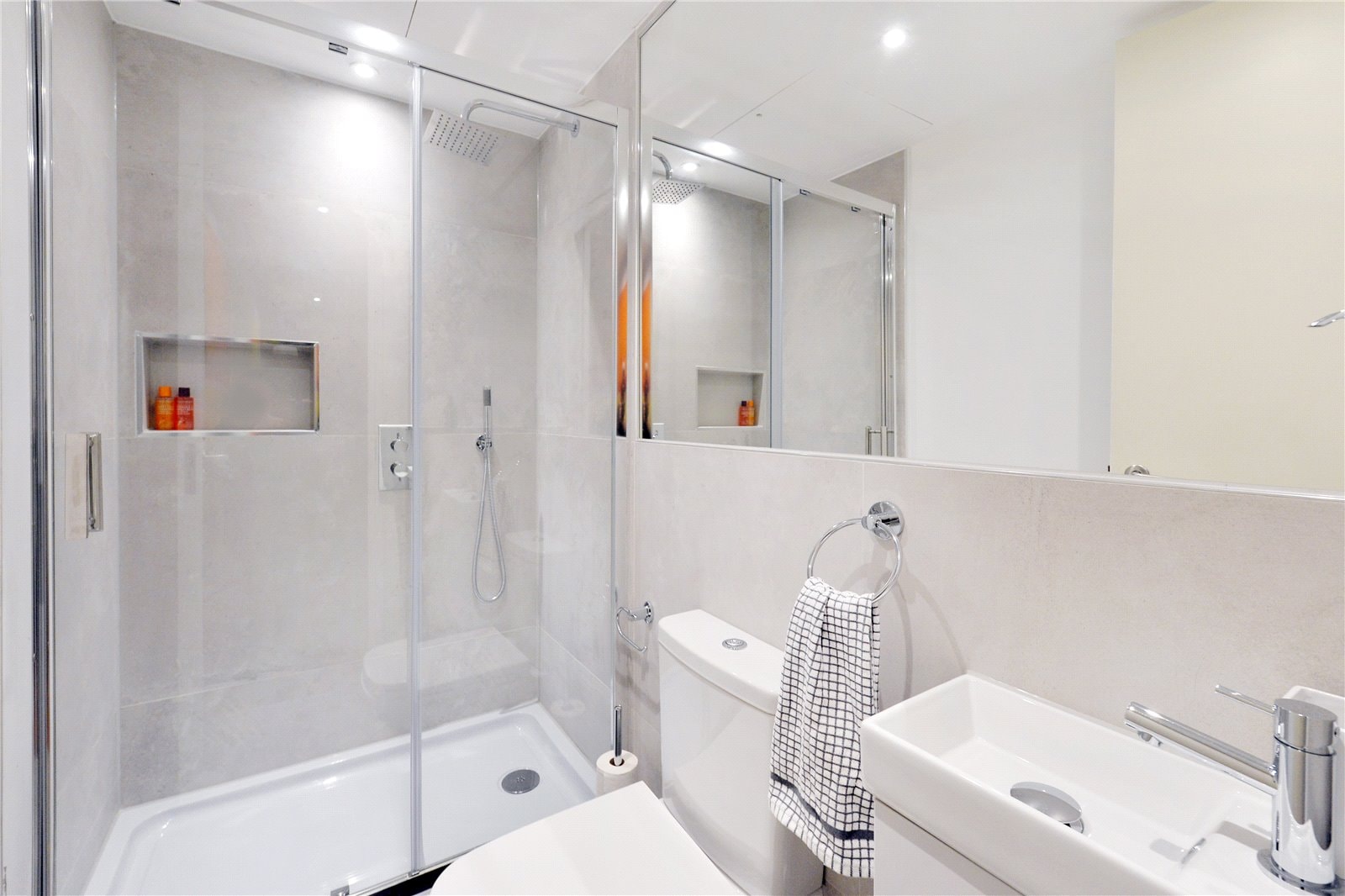 Modern sleek shower room with glass enclosure, minimalist fixtures, and neutral tones. Ideal for luxury property presentations.