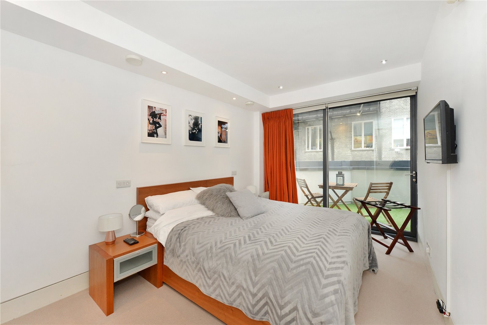 Contemporary bedroom with balcony access, stylish decor, and modern furniture in a London property.