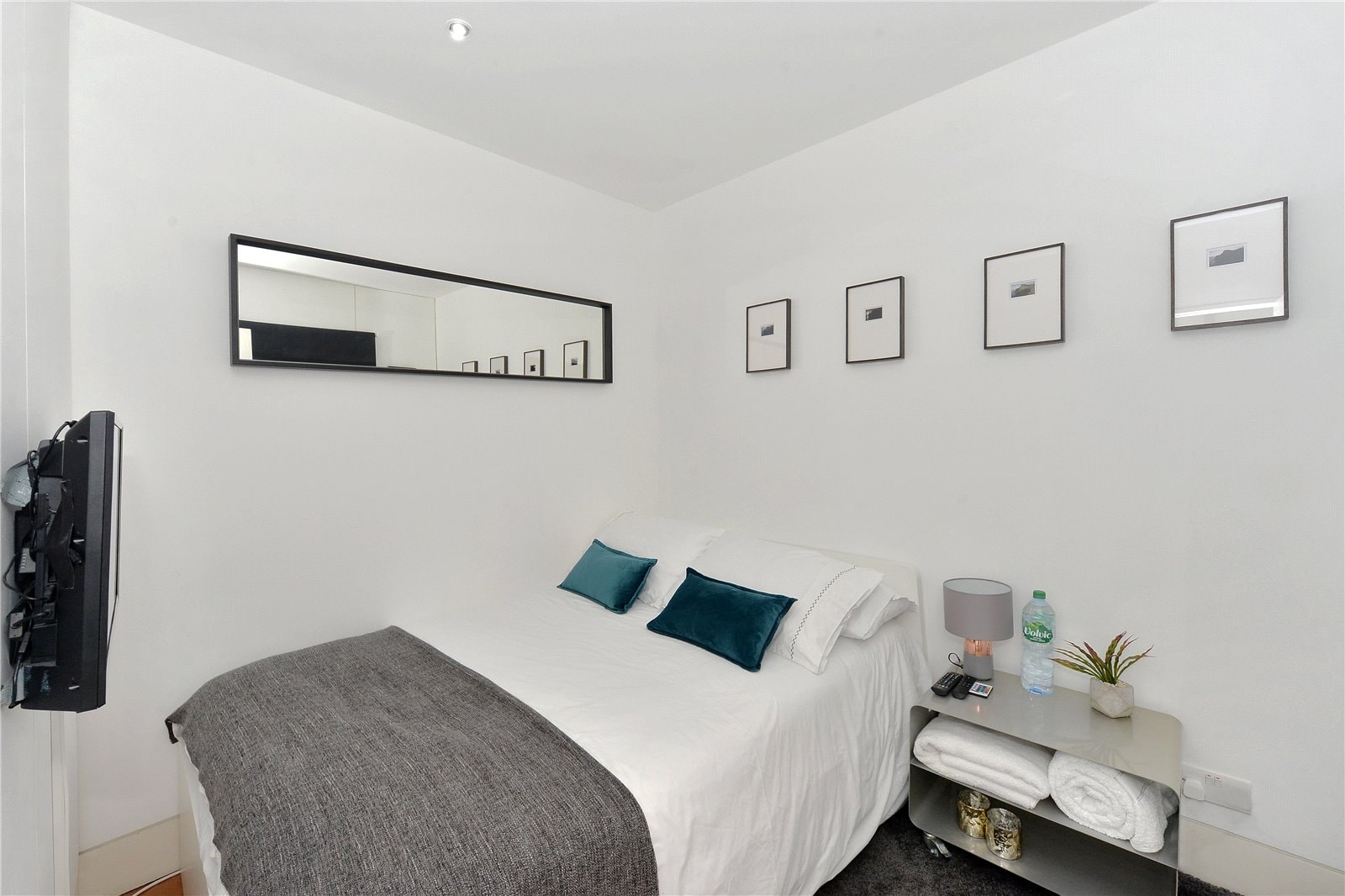 Modern white bedroom with minimalist decor, art prints, and stylish furnishings for a contemporary London property.