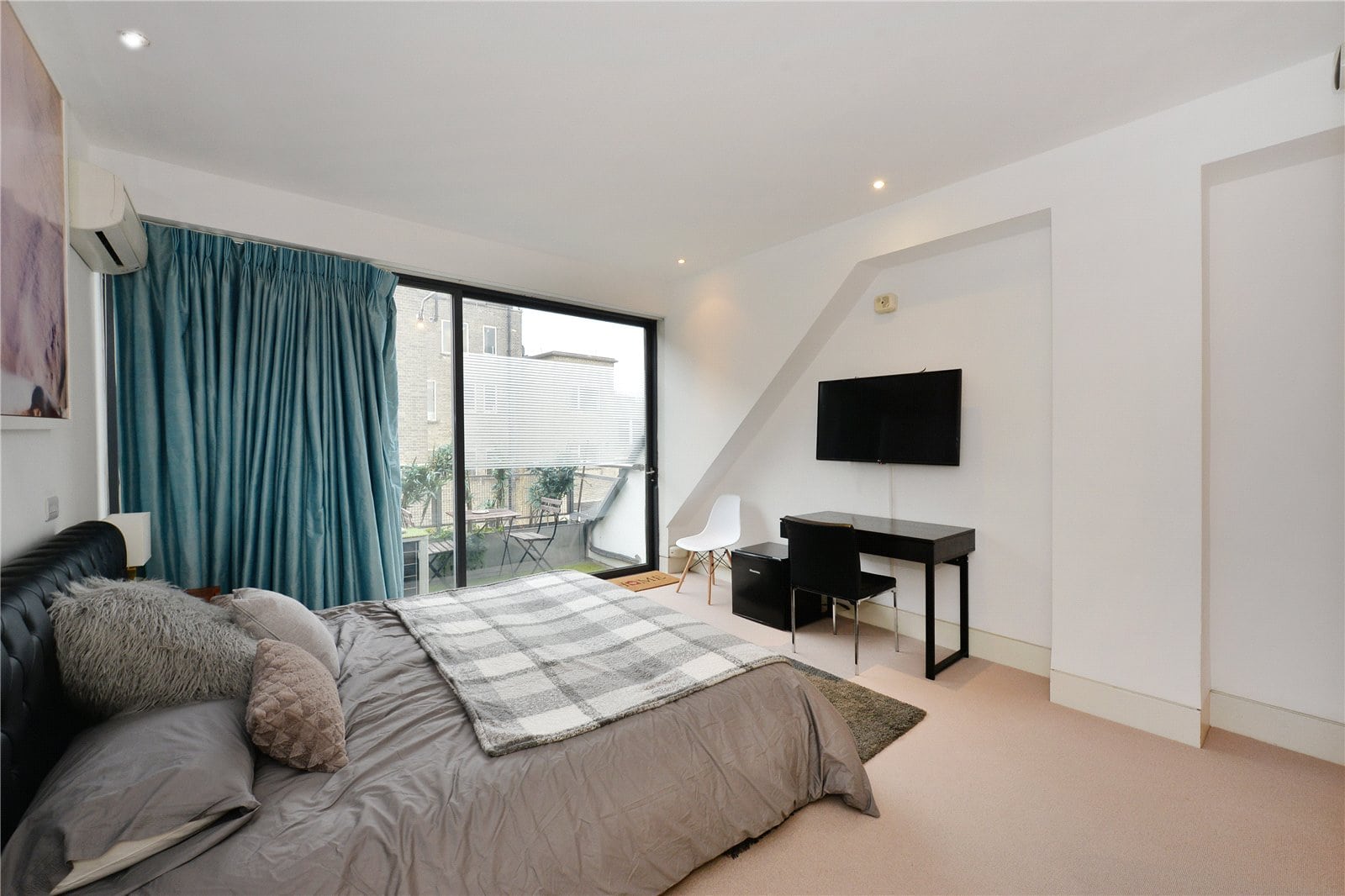 Luxury London apartment bedroom with balcony views, modern decor and stylish furnishings.
