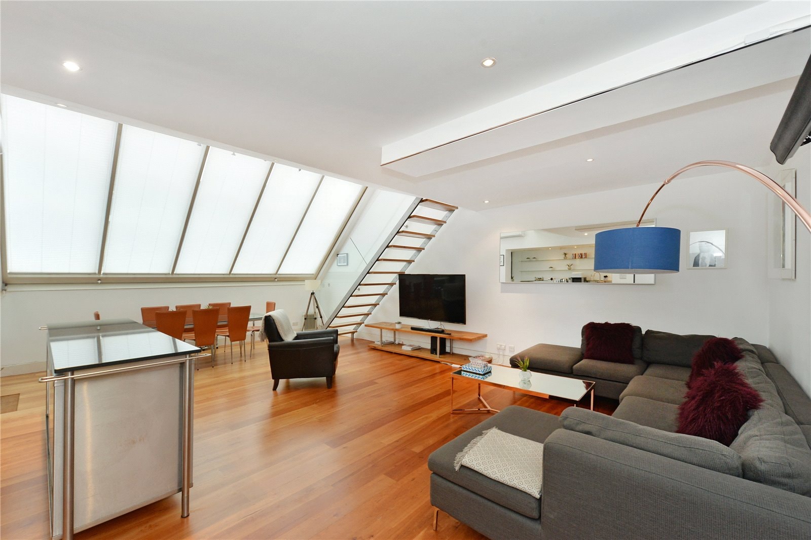 Bright, modern loft living room with large skylight, open-plan design, hardwood flooring, stylish furniture, and contemporary decor - perfect for London apartments.