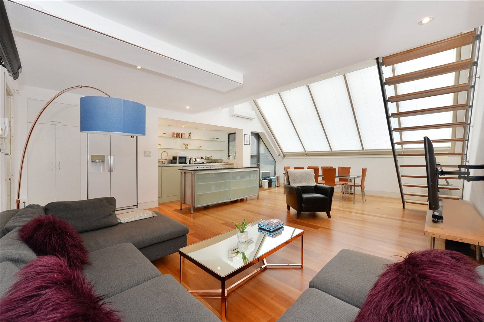 Bright contemporary living room with large skylights, modern furniture, and open-plan kitchen in a stylish apartment.