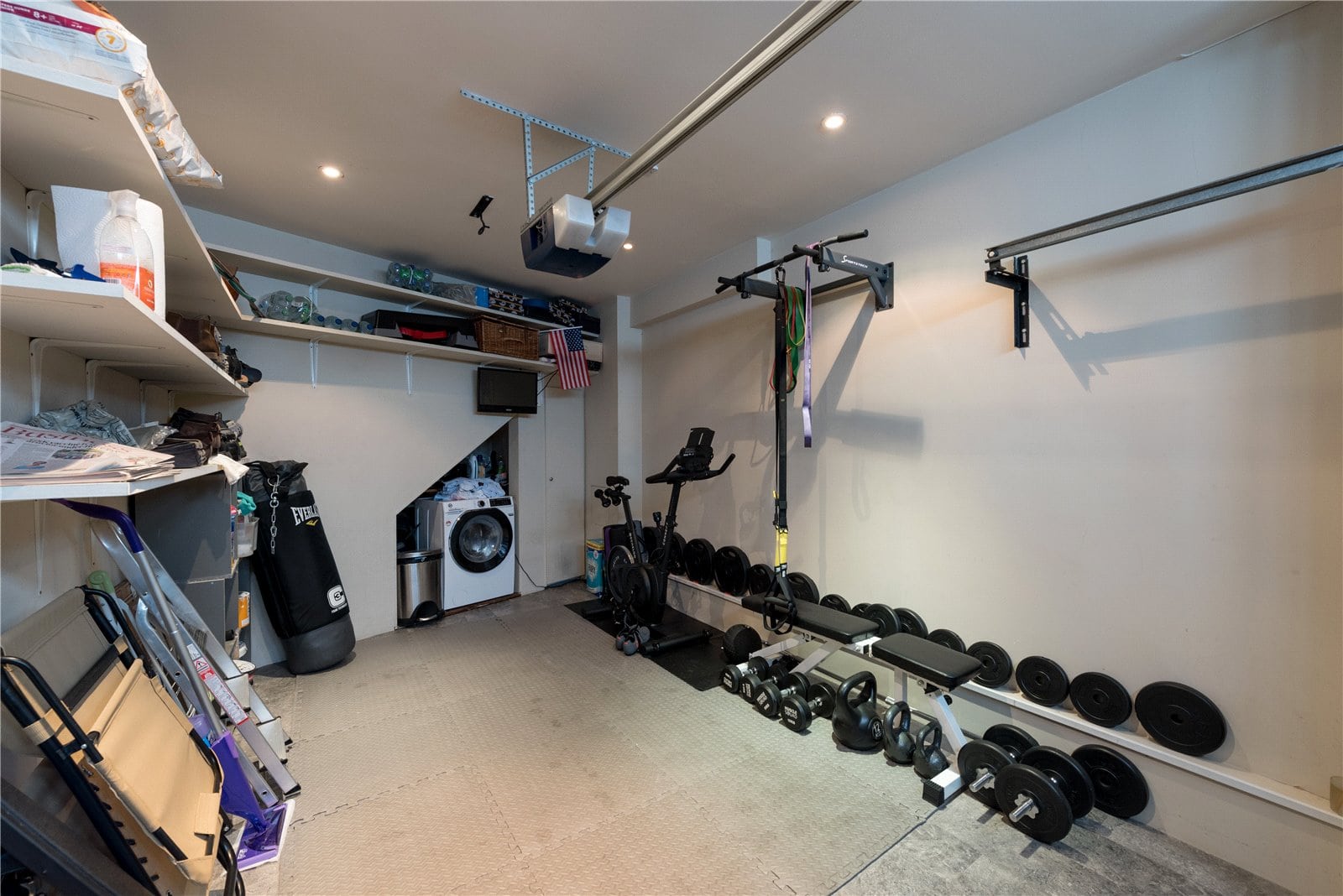 Organised garage with fitness equipment, weights, and storage shelves for home gym and storage solutions.
