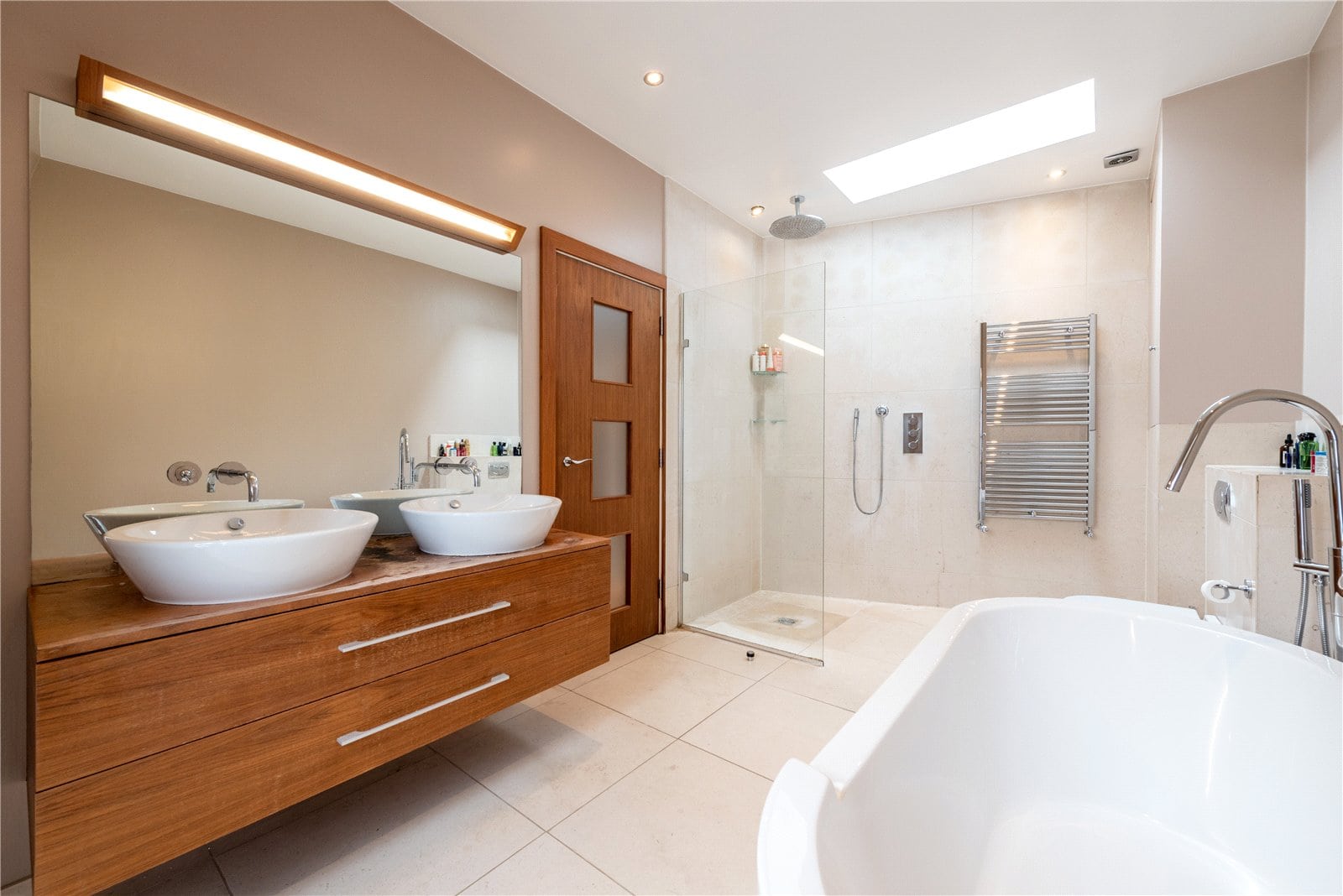 Modern luxury bathroom with double vessel sinks, walk-in shower, and bathtub, featuring sleek design and high-end fixtures.