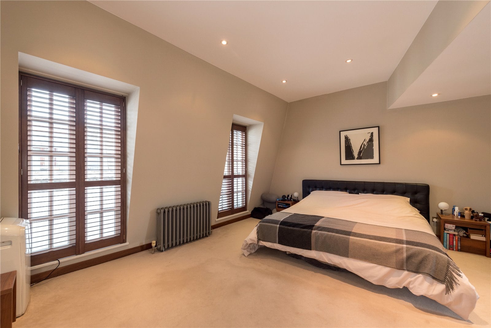 Bright modern bedroom with large windows, wooden shutters, and contemporary decor in a high-end property.