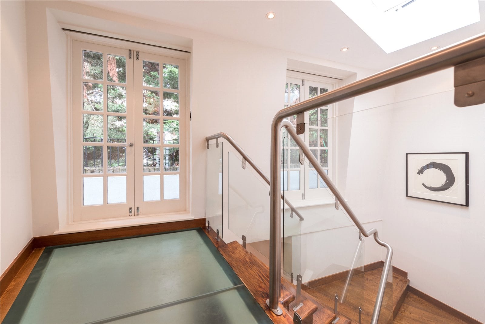 Bright contemporary stairwell with large windows and glass railing, stylish interior design at Lurot Brand property.