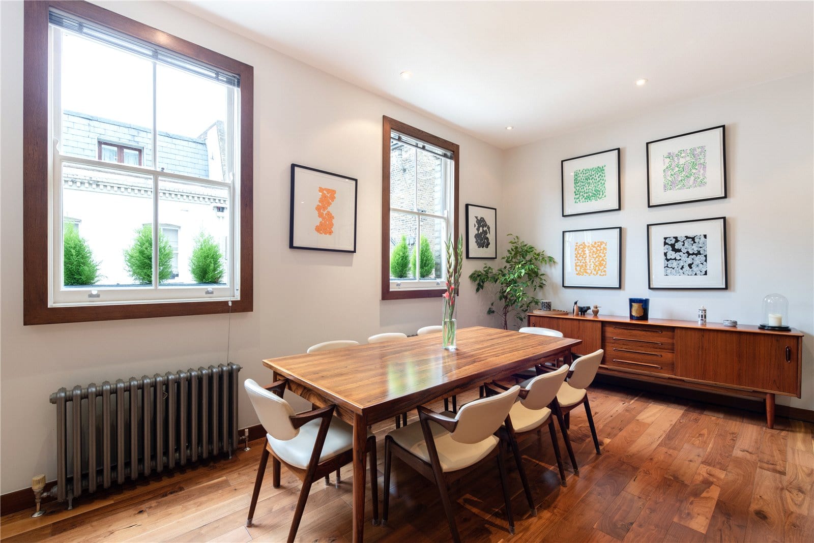 Modern dining room with wooden table and artwork, bright natural light from double-glazed windows.