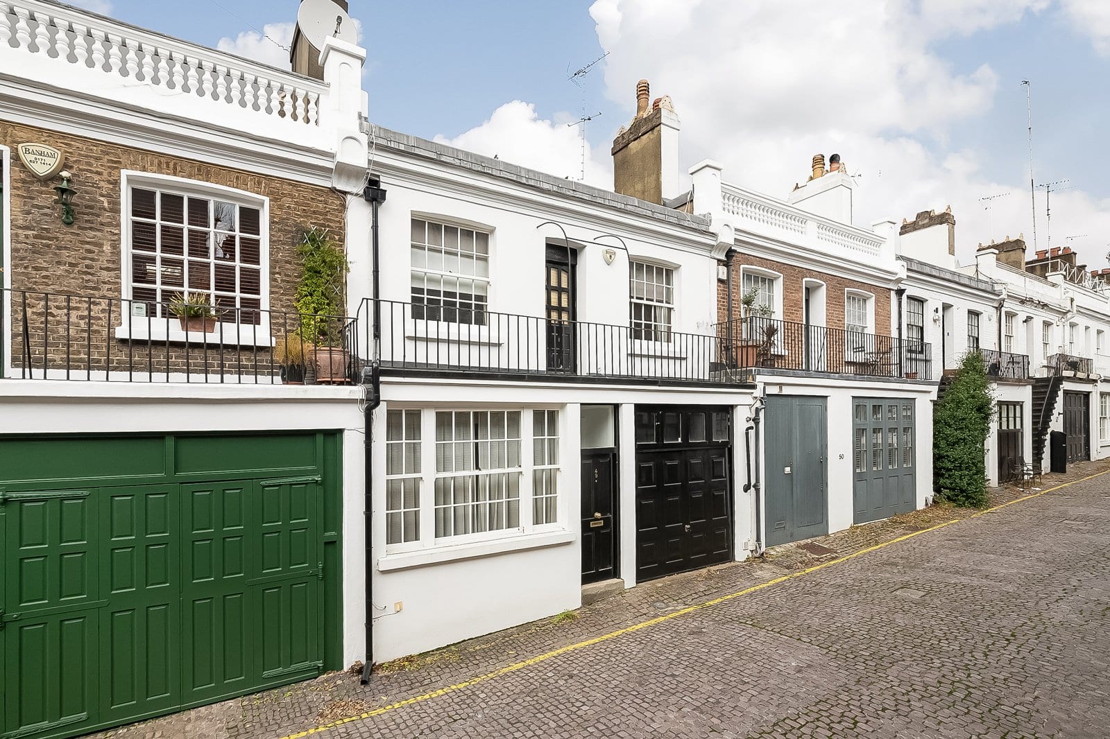 Charming row of Georgian townhouses in London with colourful garage doors and classic architecture, perfect for property investment.