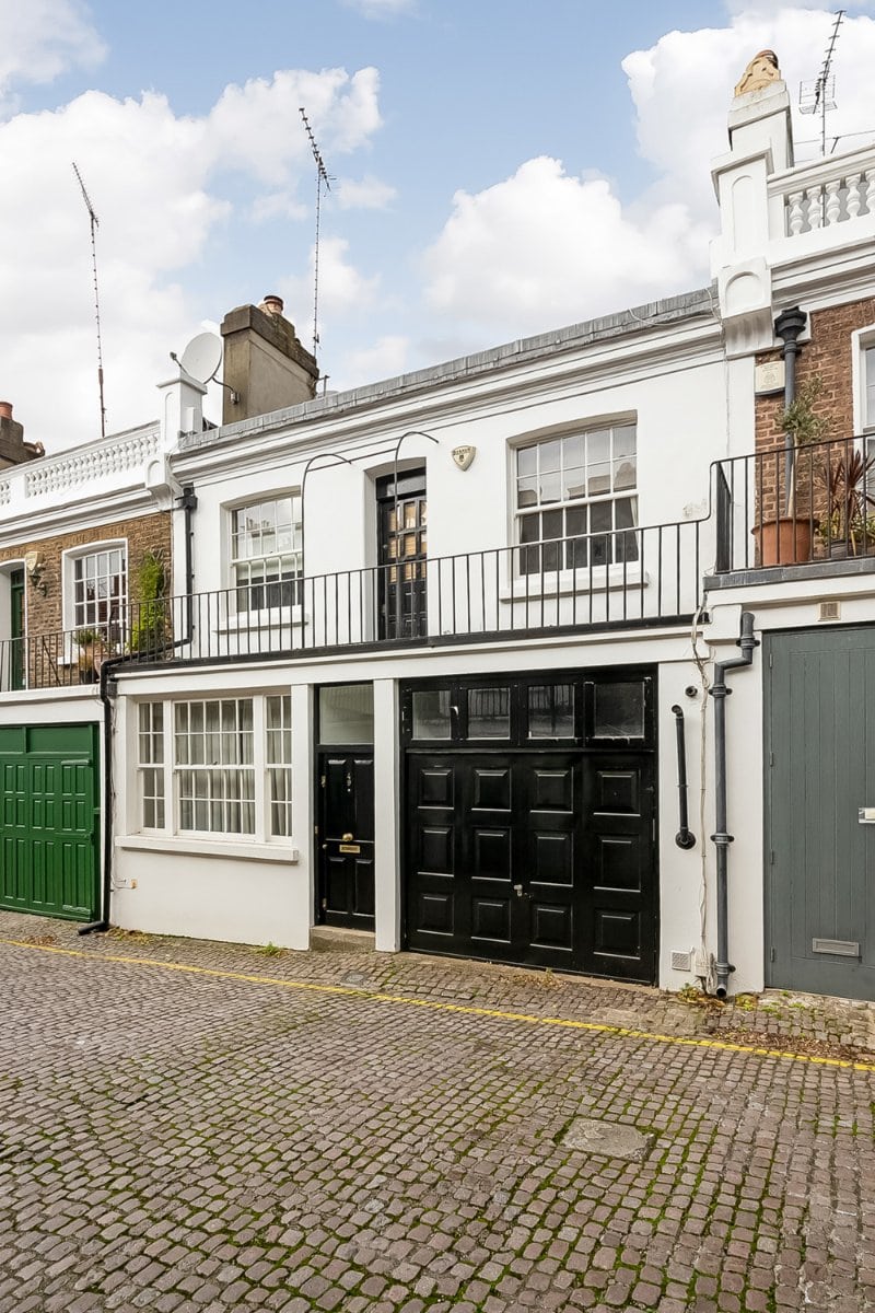 Charming Georgian terraced house with black and white façade, cobbled street, and classic London architecture.