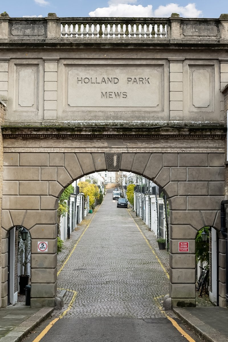 Holland Park Mews entrance in London, historic arches and cobbled street, picture of a London residential alleyway.