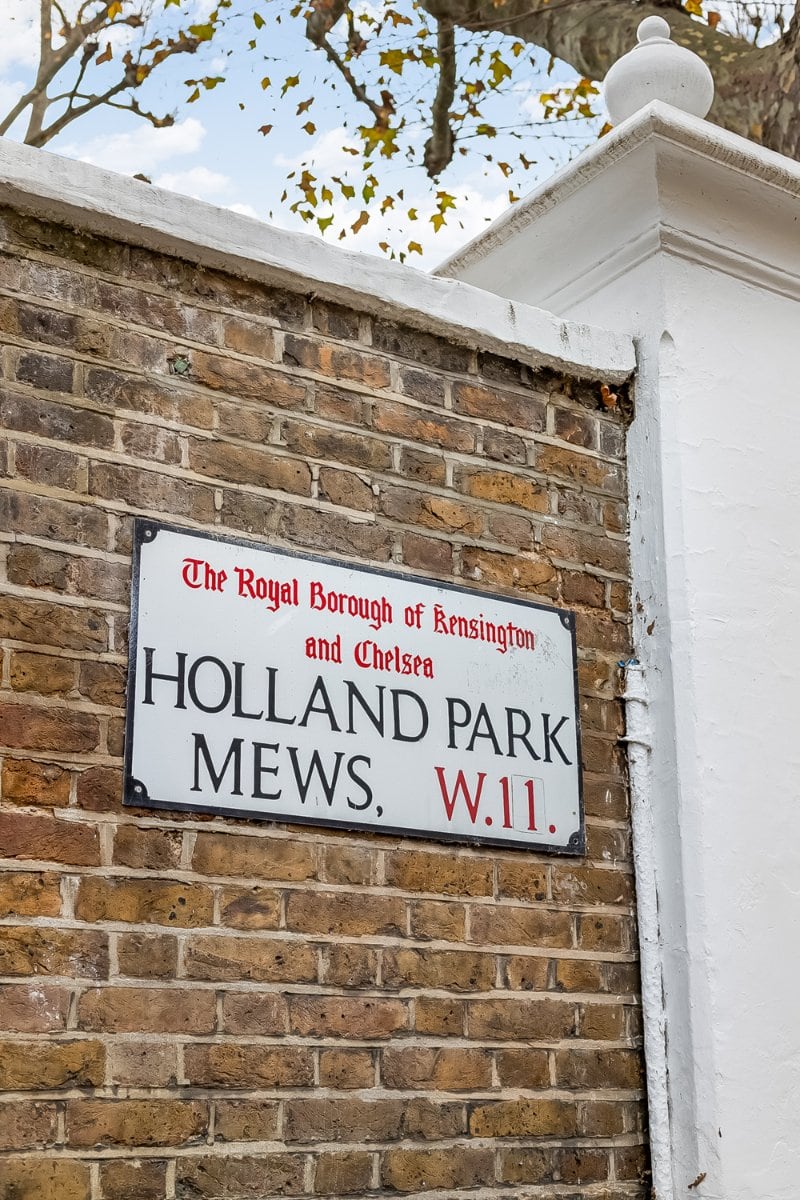 Old brick wall with Holland Park Mews, W11 street sign in Kensington, London.