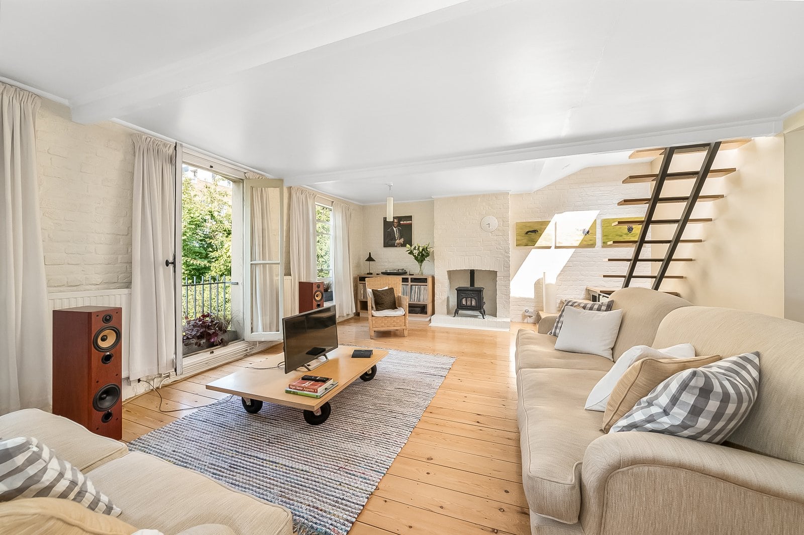 Bright living room with large windows, cosy fireplace, and contemporary interior design.