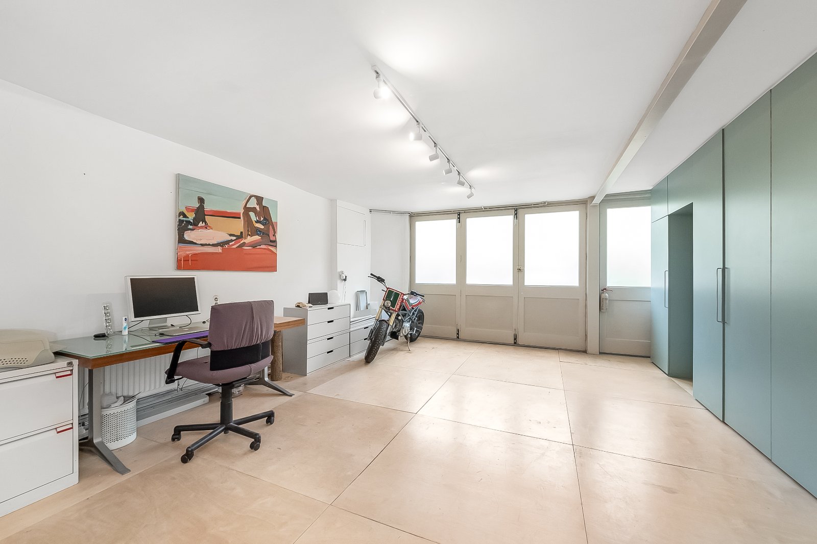 Bright modern office space with large windows, white walls, and minimalist furniture in a contemporary London property.