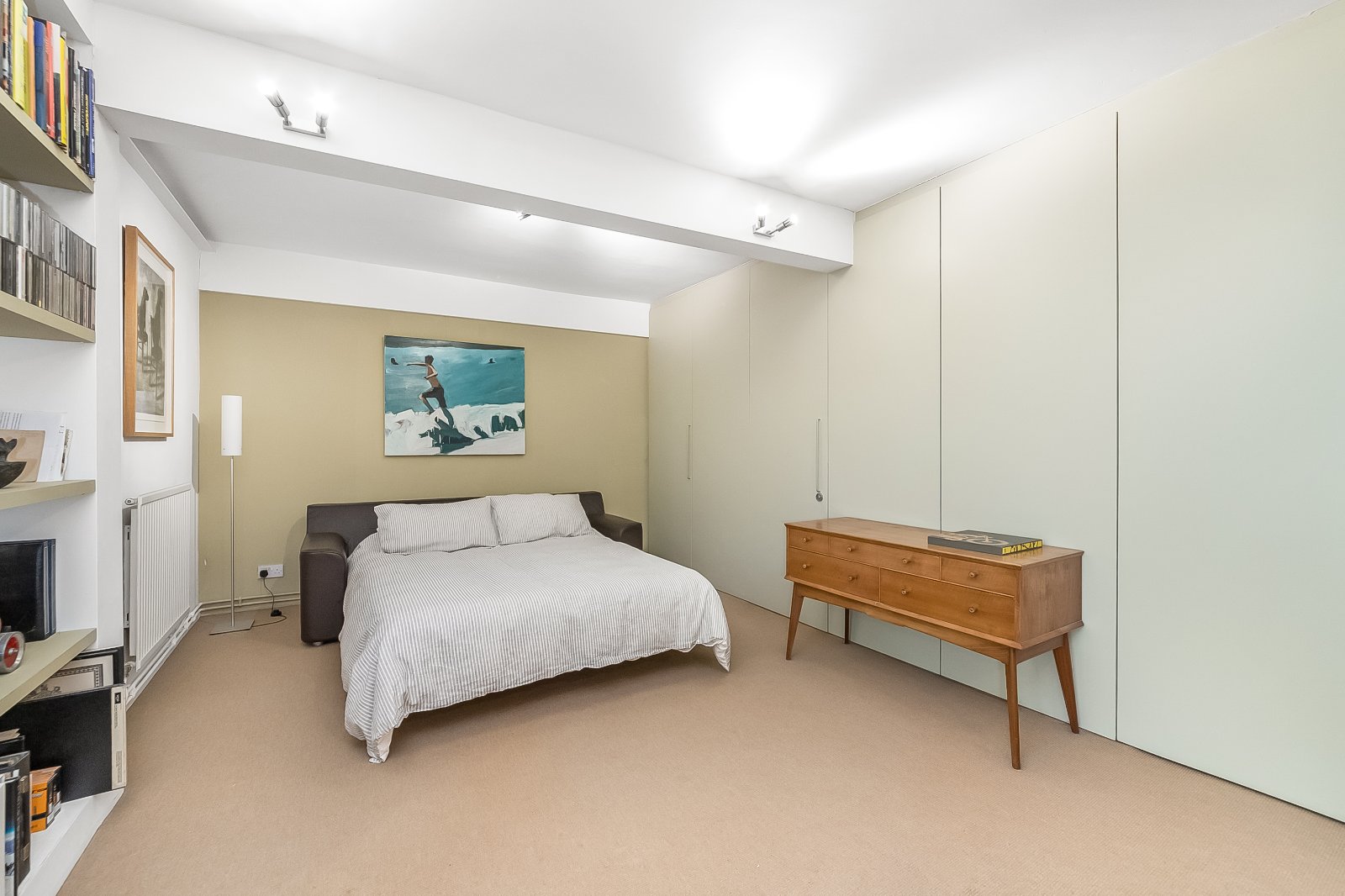 Modern minimalist bedroom with neutral tones and stylish decor in London property, featuring a comfortable double bed, artwork, and built-in storage.