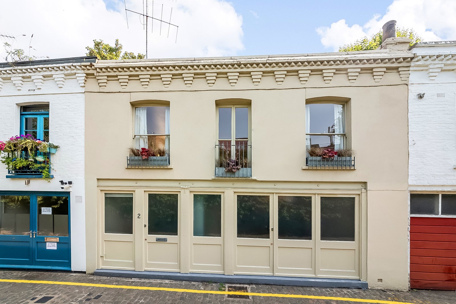 Charming two-storey historic building with large windows and decorative façade details, located in a scenic urban setting.