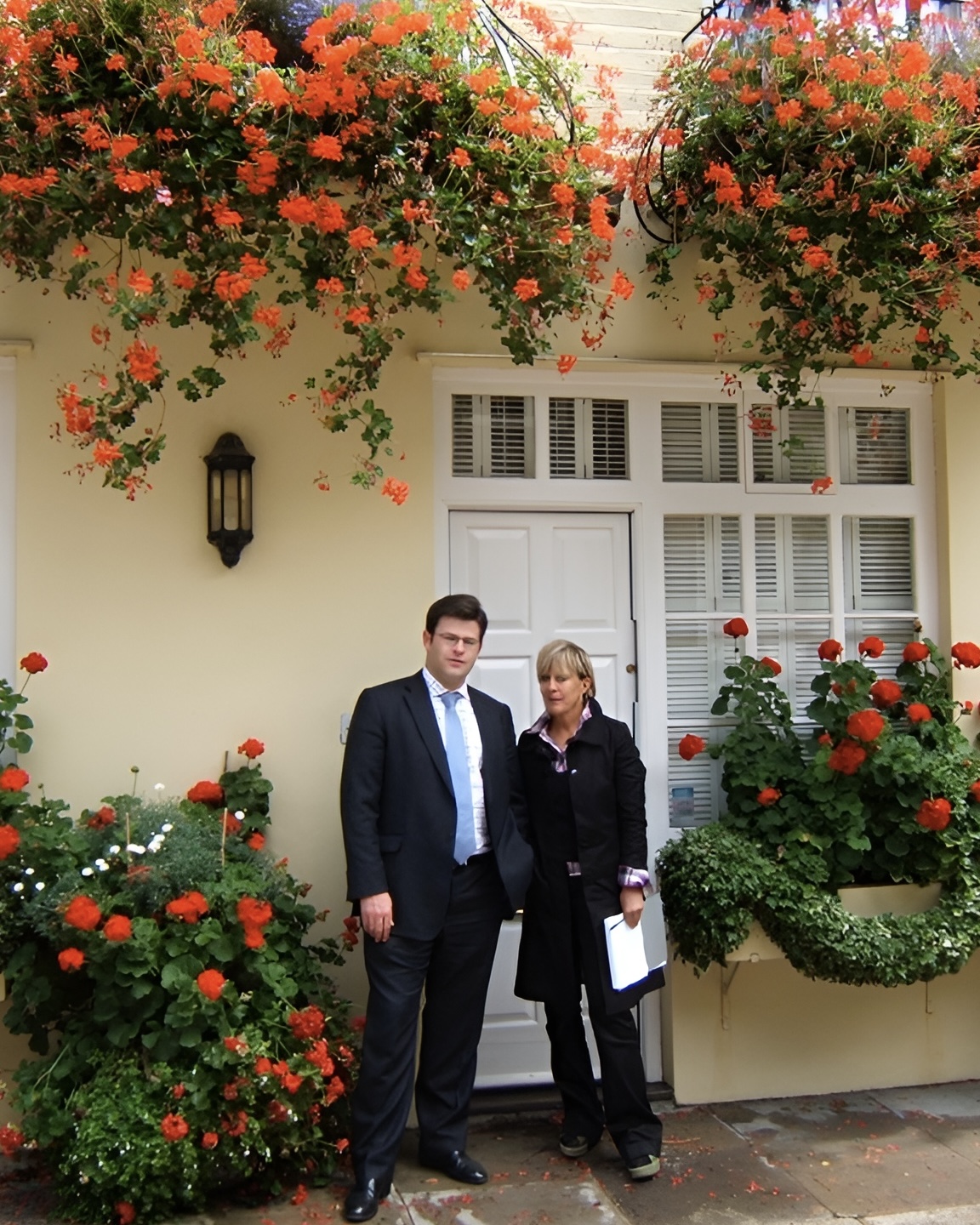 Candida Lycett and Oliver Lurot standing in front of a mews house with flowers blooming