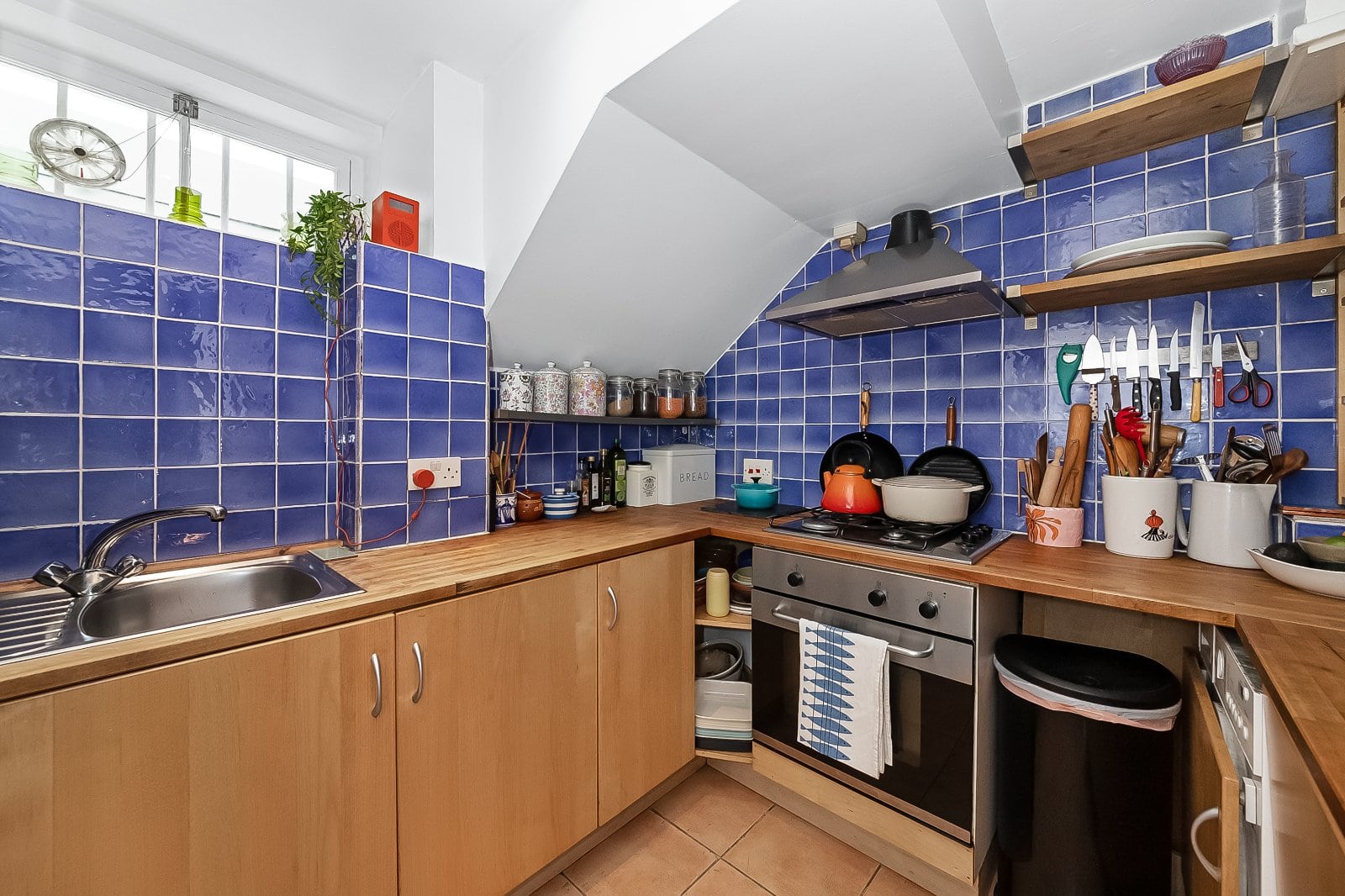 Bright kitchen with blue tiled walls and wooden countertops featuring modern appliances and colourful kitchenware.