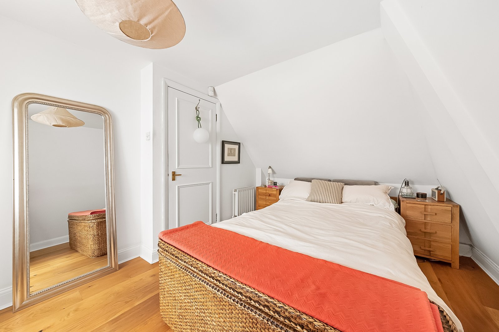 Bright minimalist bedroom with sloped ceiling, wooden furniture, and cosy decor, perfect for modern London living.