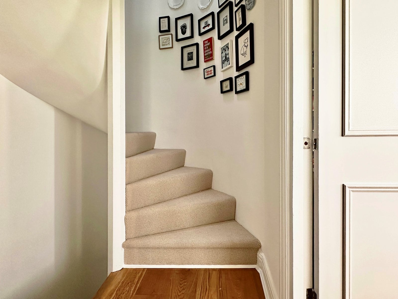 Modern interior stairway with beige carpet and stylish gallery wall with picture frames.