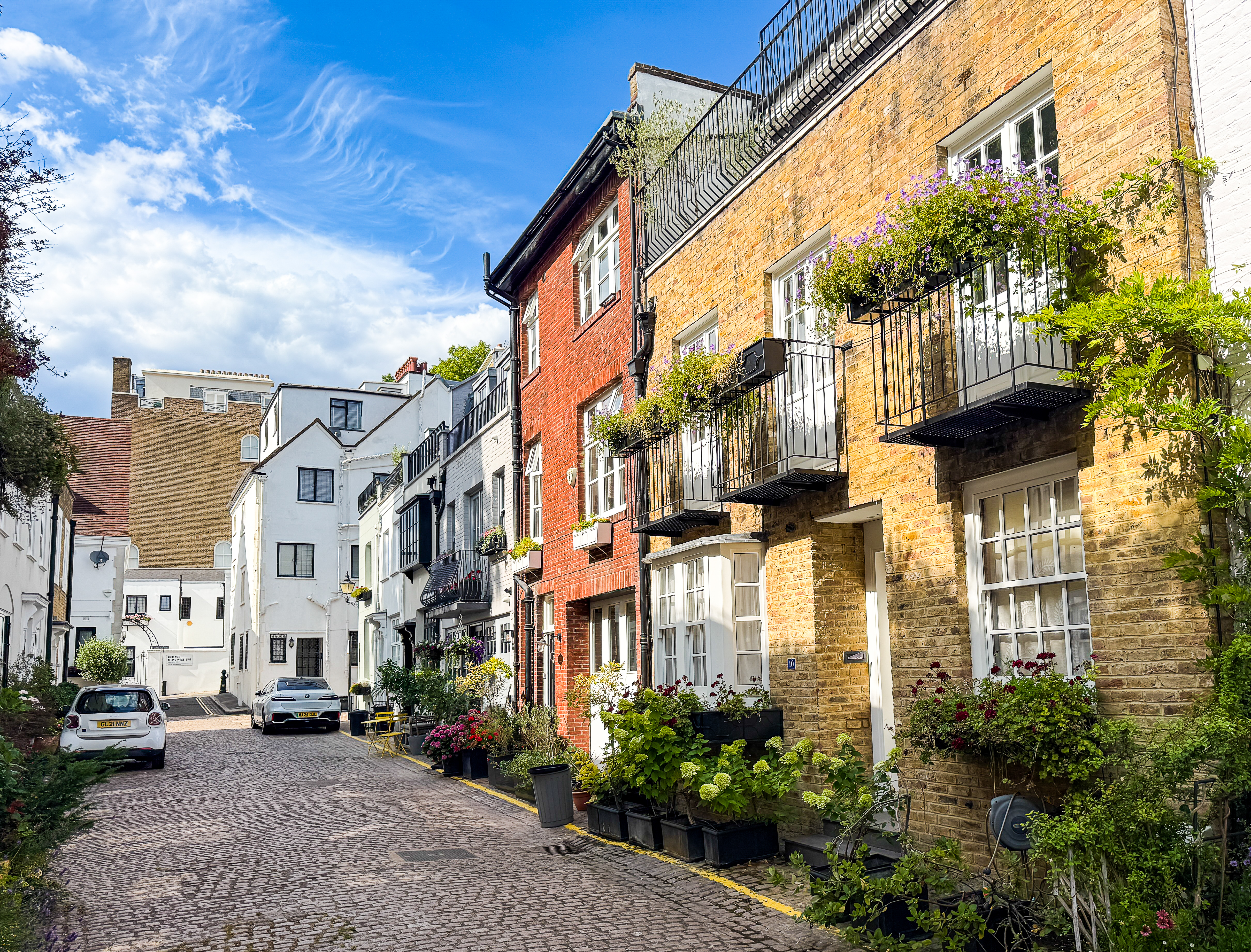A Mews Street In London With A Yellow And Orange Mews House