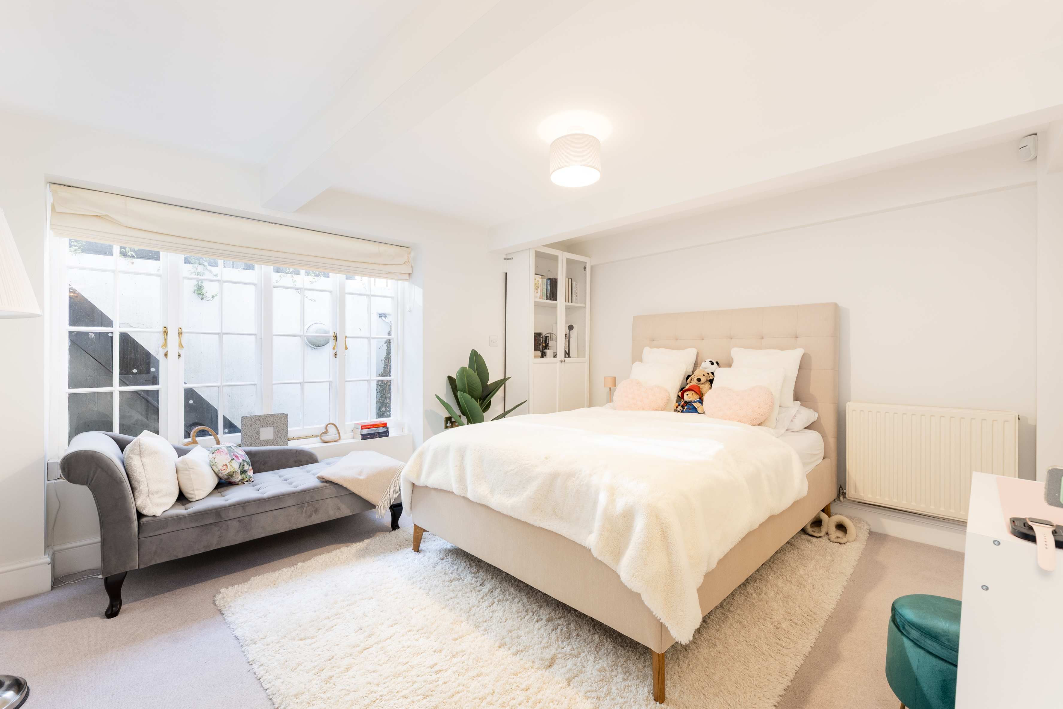 A large bedroom with a double bed and a small sofa in a property to rent in London