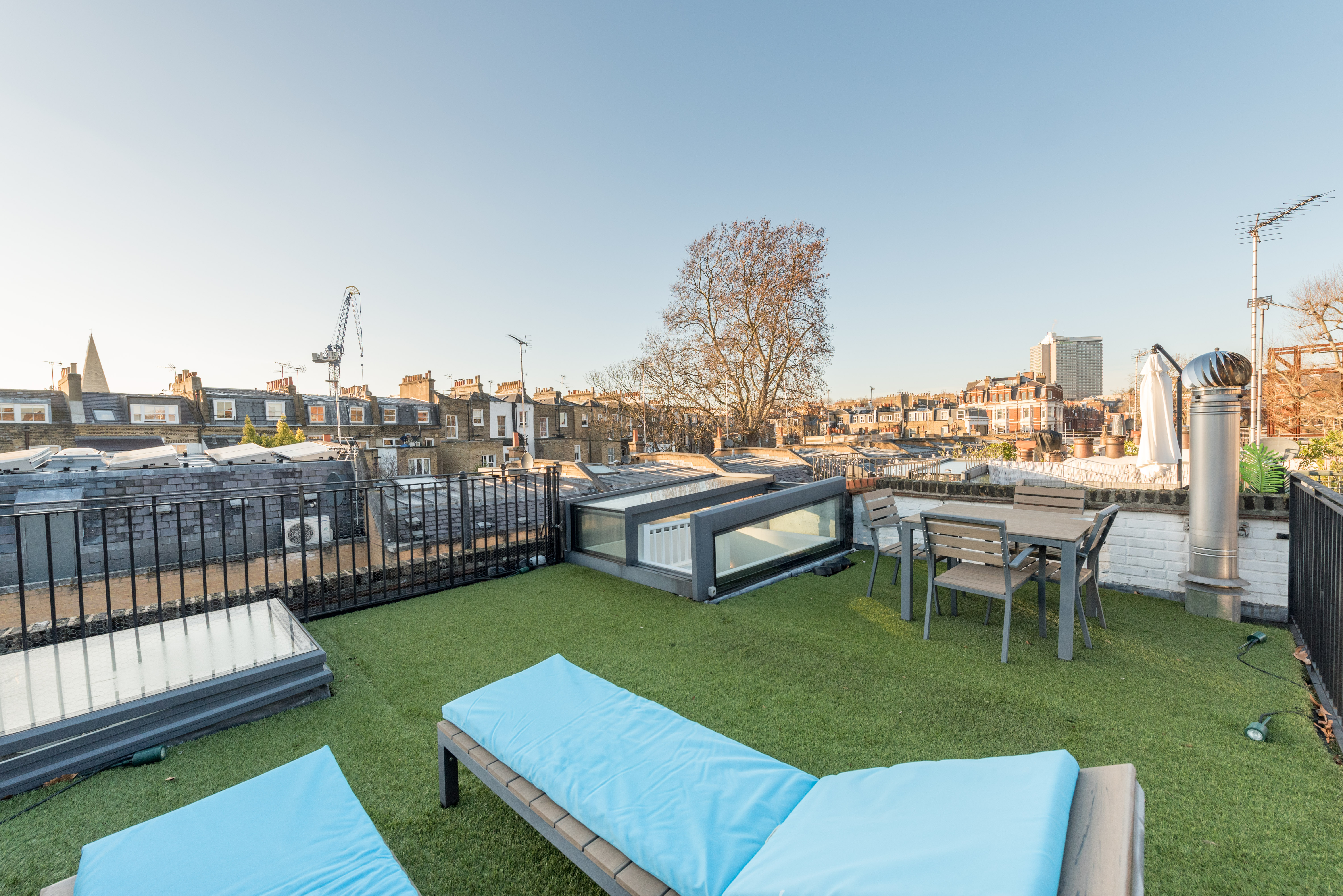 A spacious roof terrace with two sun beds on top of a mews property