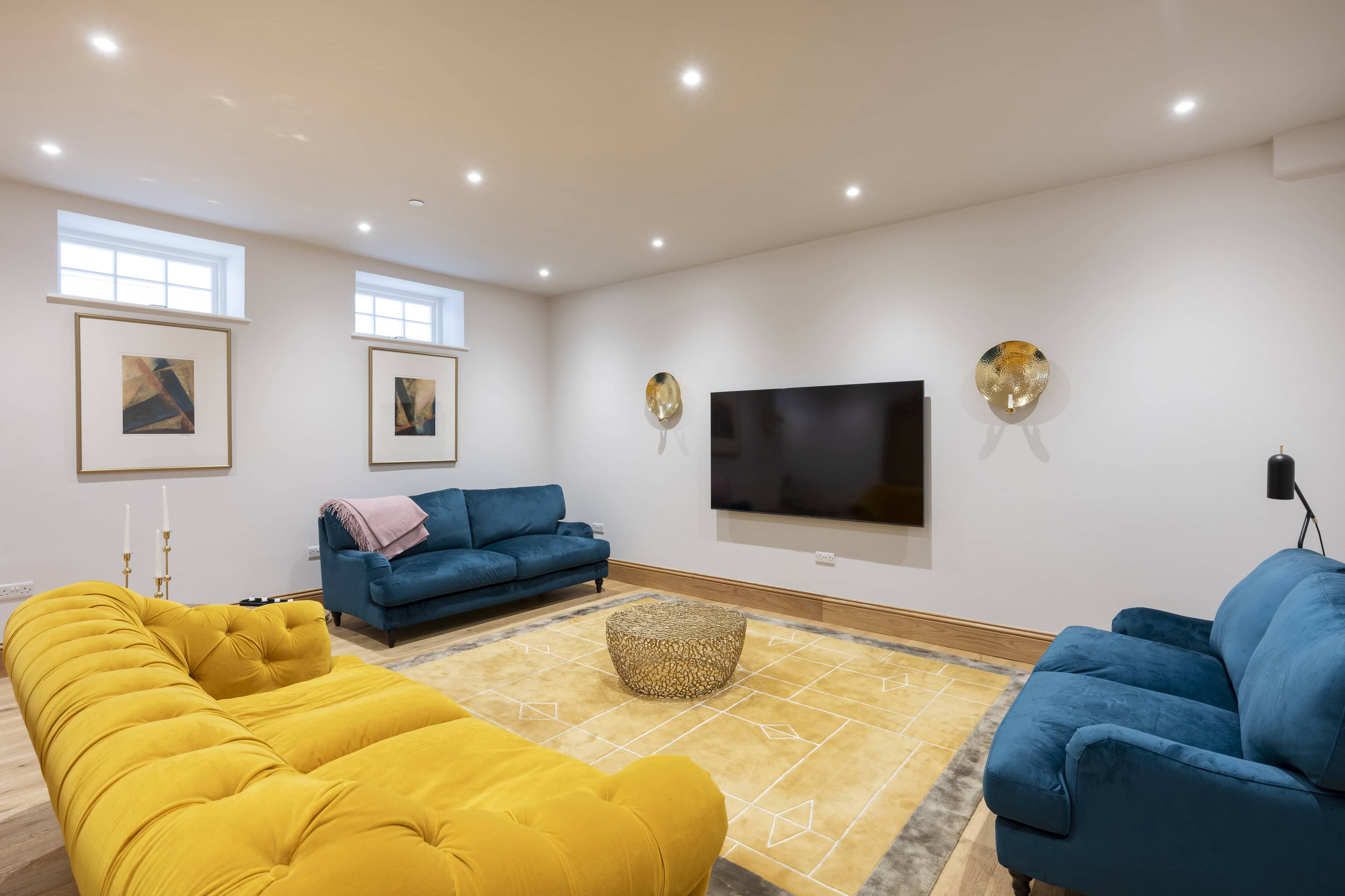 A Living Room In A Mews Property With Blue And Yellow Sofas And A Tv Attached To The Wall