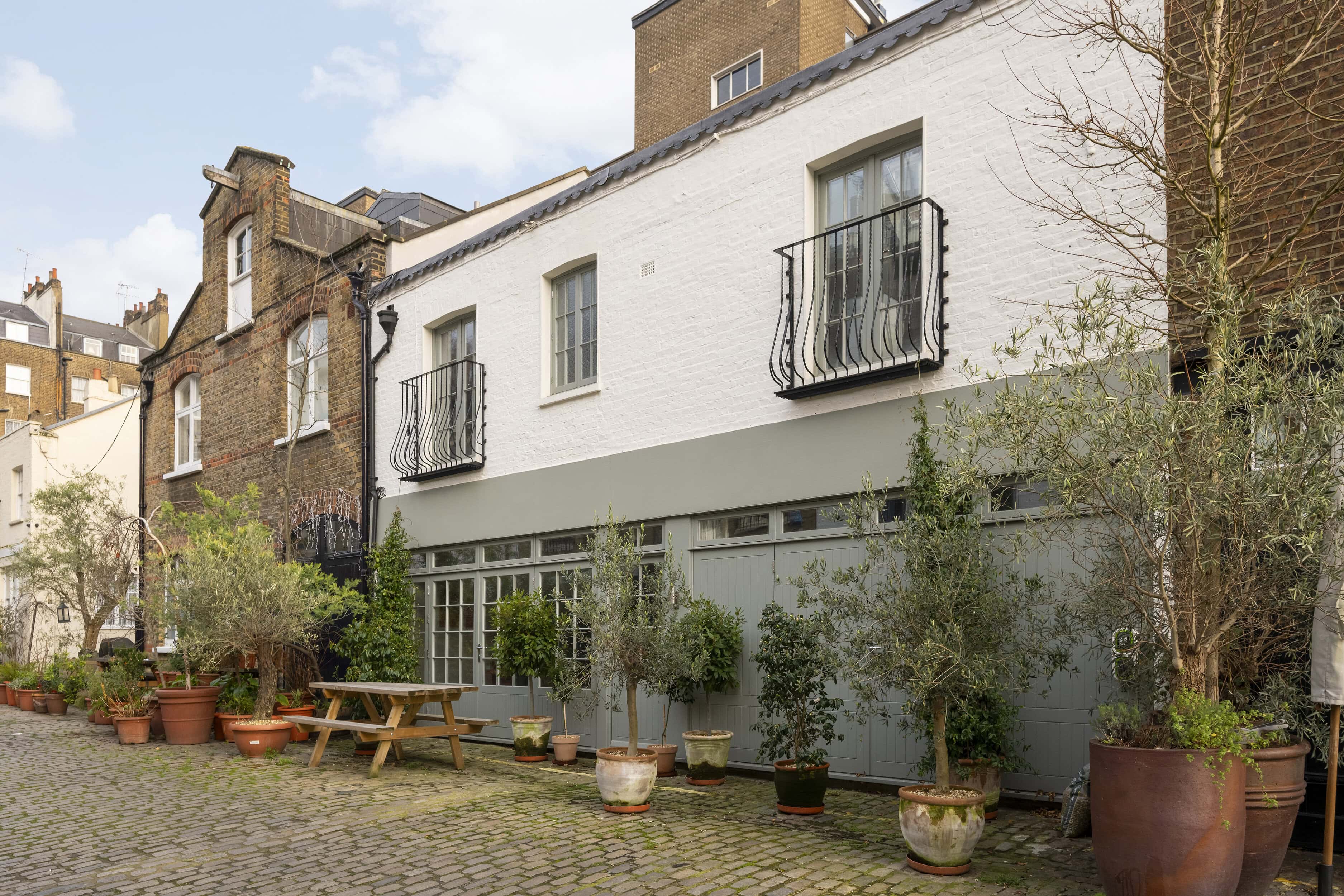 A White A D Grey Mews Property With Plants Outside The Windows