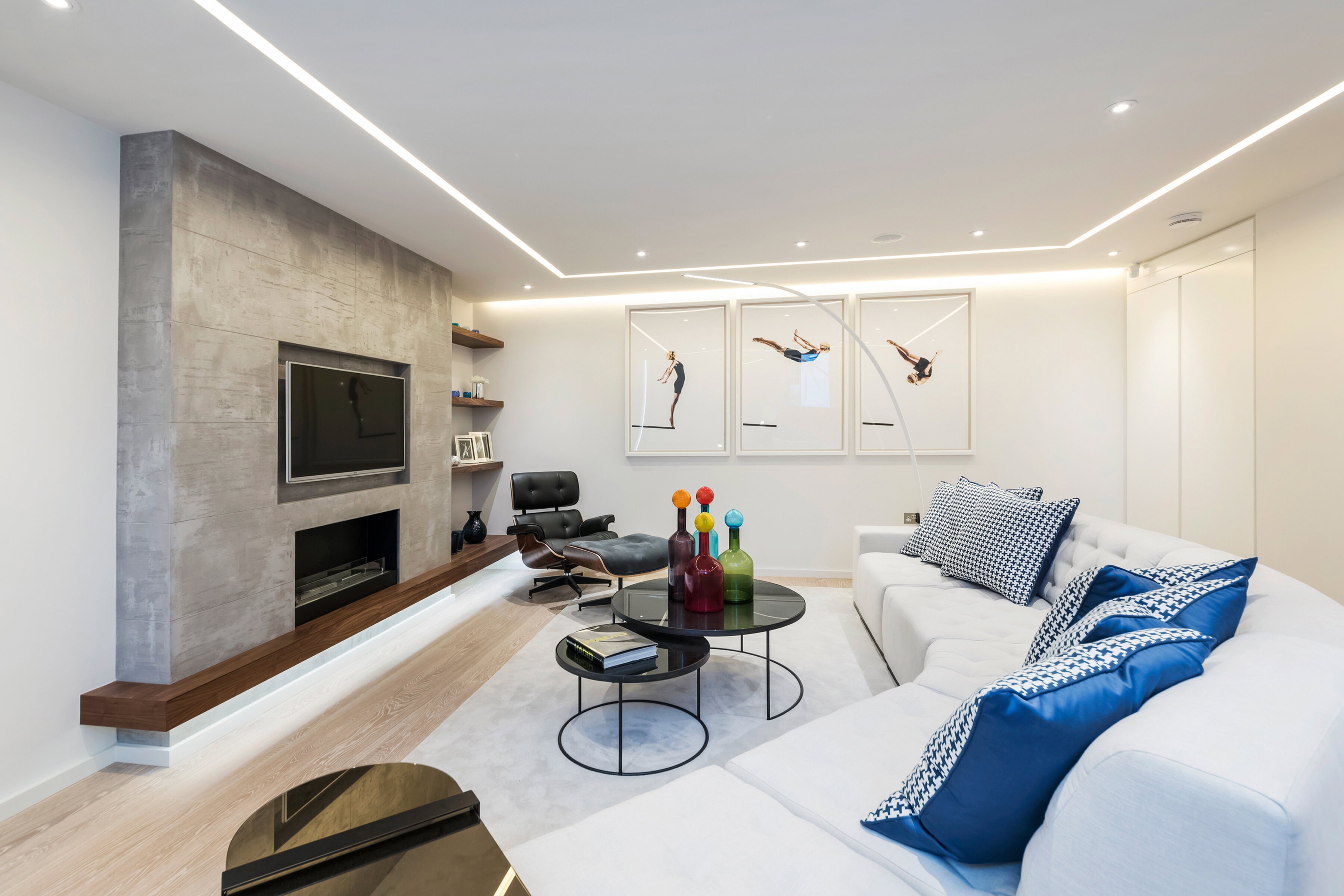 A sitting room with a tv and a white sofa with blue cushions in a mews property