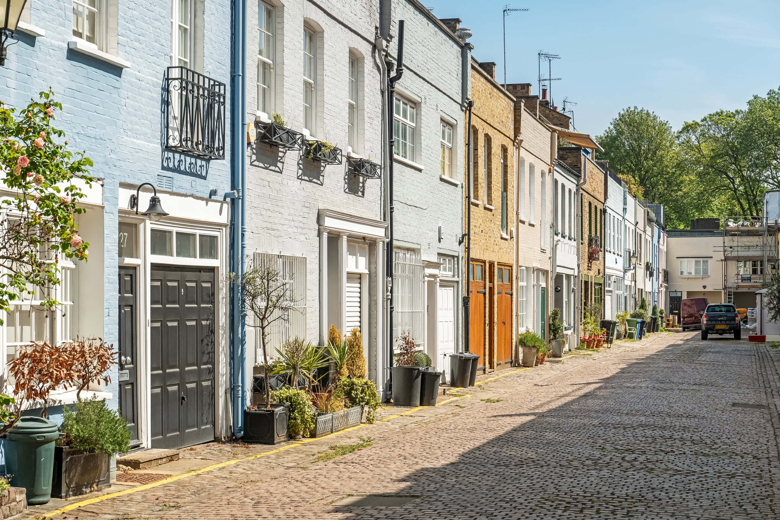 A mews street in London during Autumn with plant pots and colourful houses