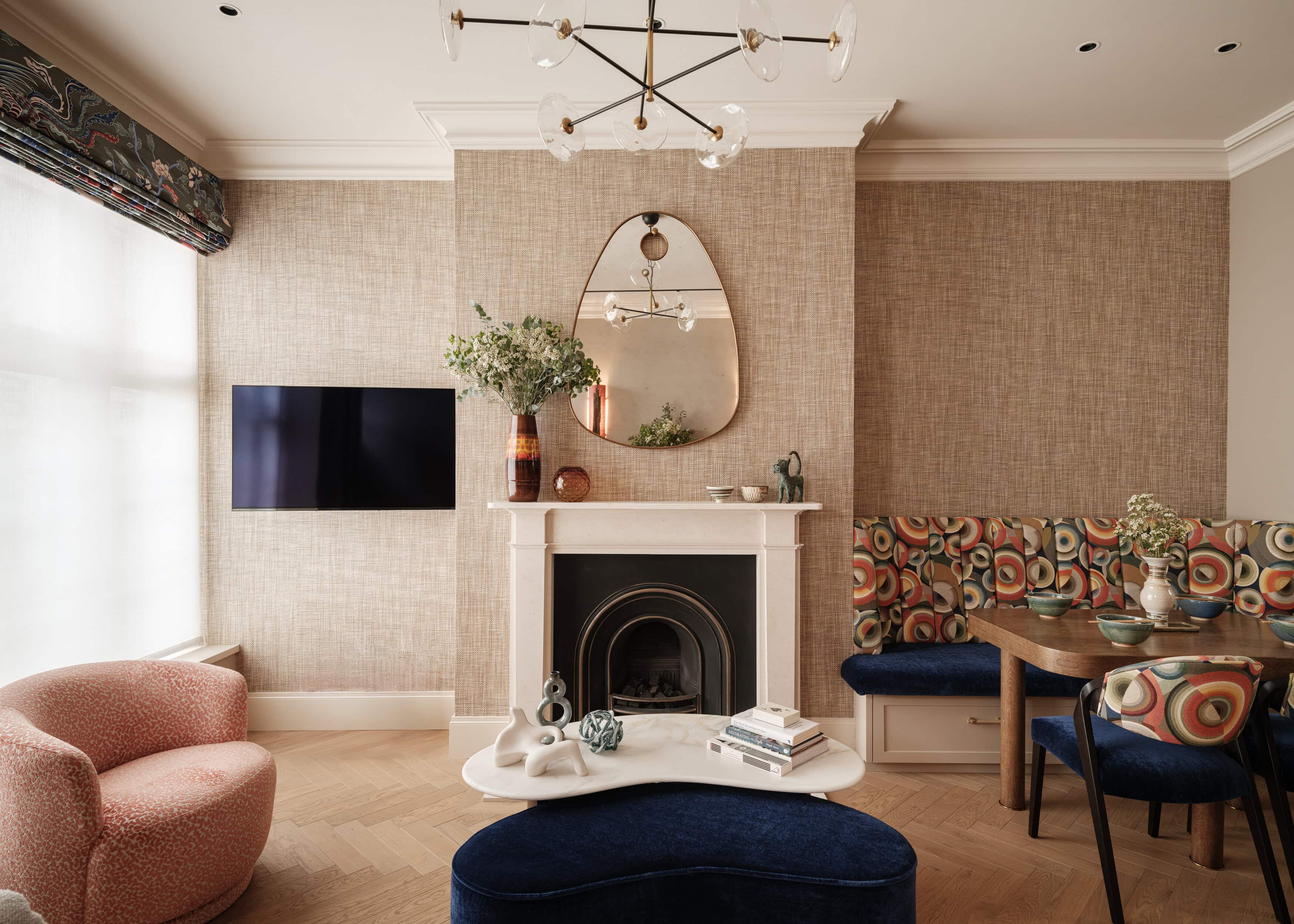 A living room in a mews property with a white fireplace, mirror on the wall and pink sofa