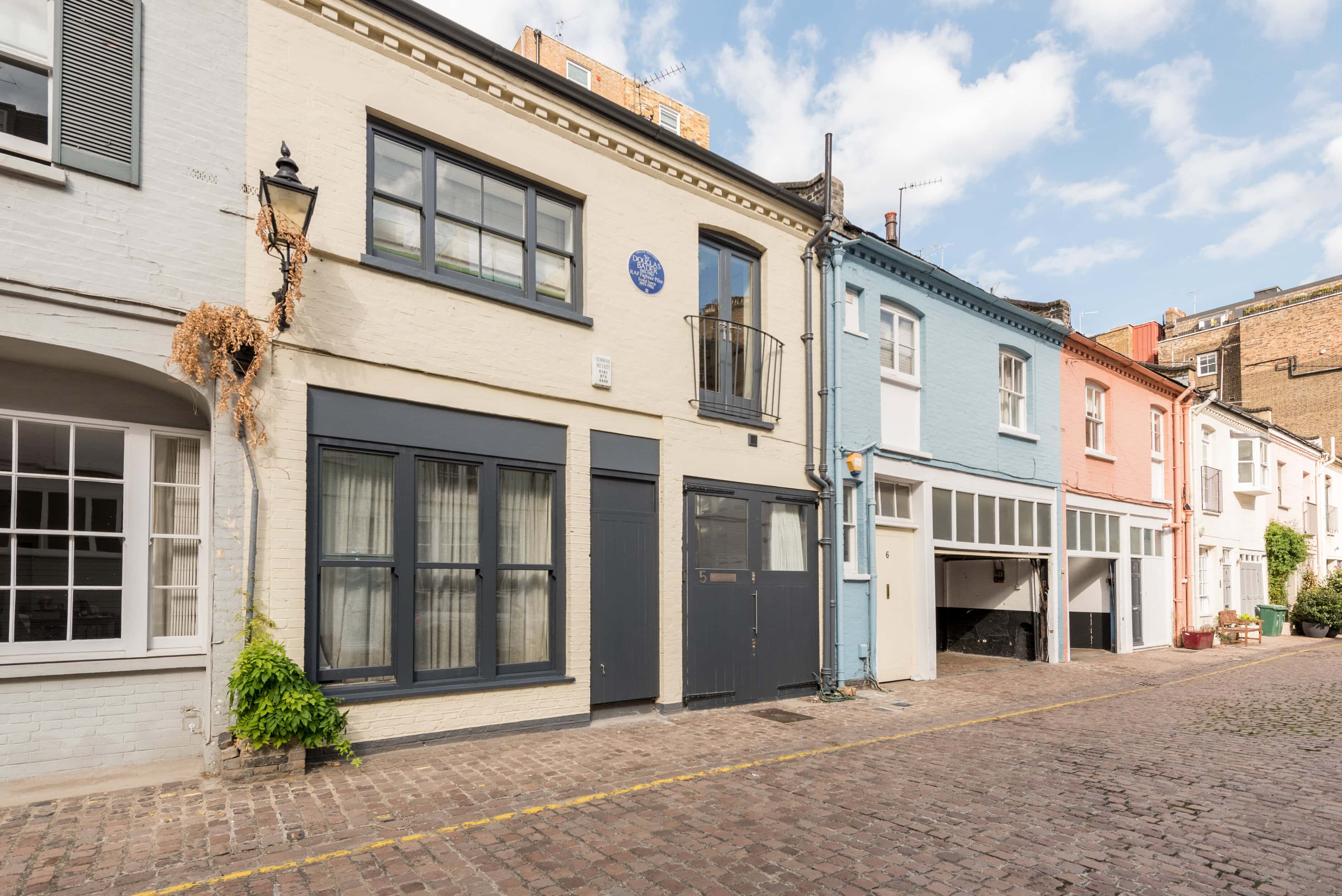 A pretty mews street with a house with a blue plaque on it