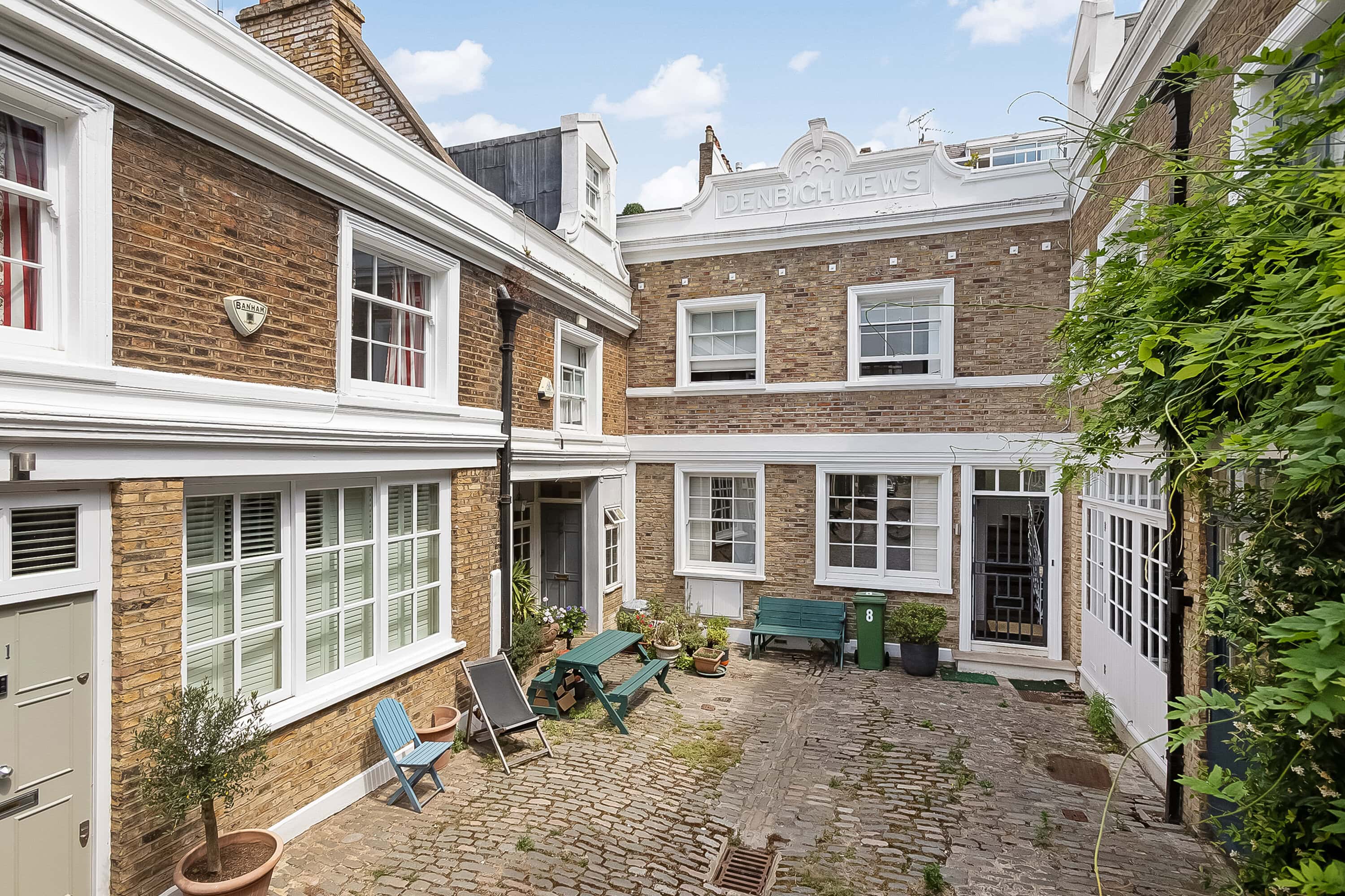 A corner mews property in a mews street with a blue bench and chairs