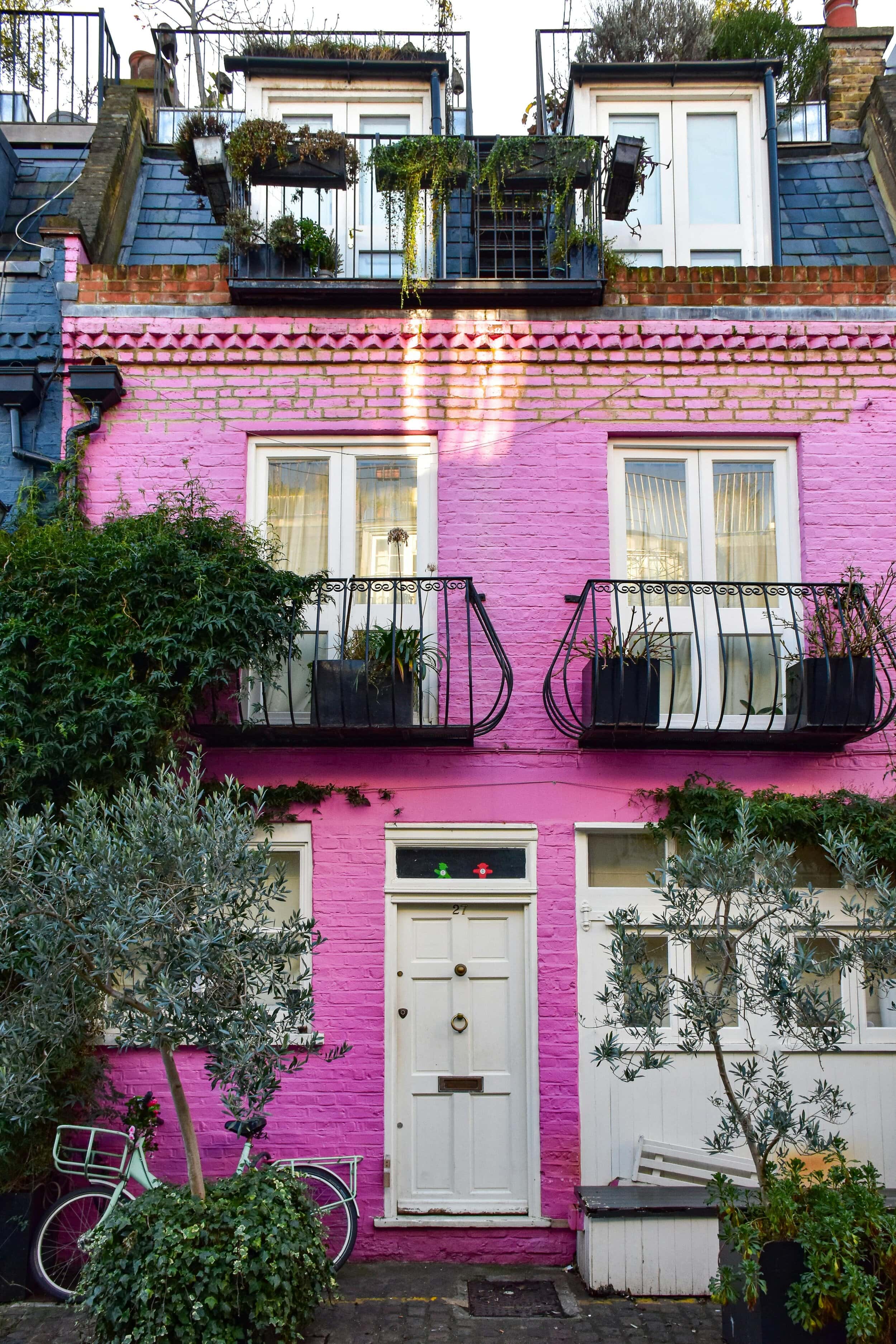 Pink mews house with black balconies and bushes