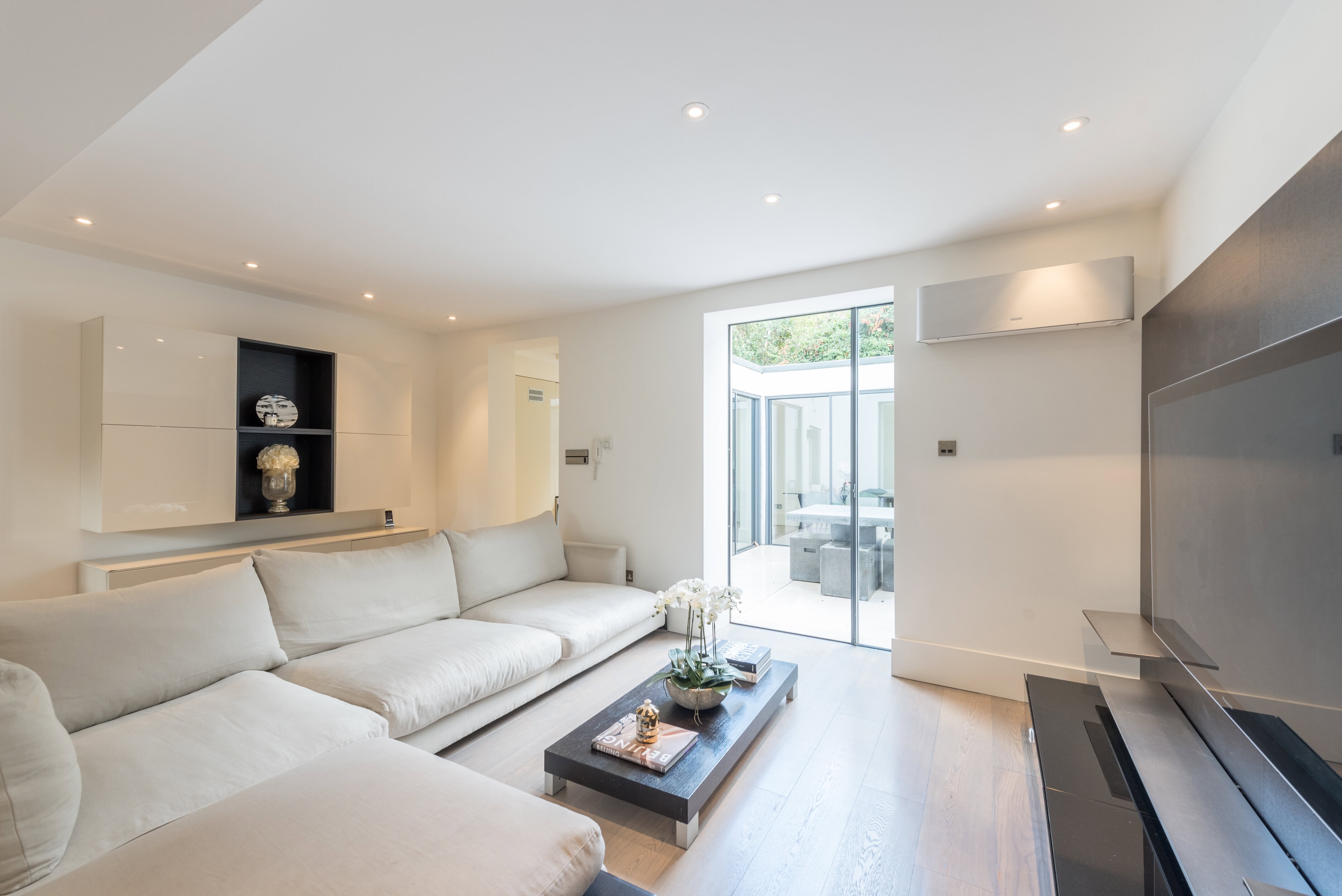 An open-plan reception room with a white sofa and outdoor access