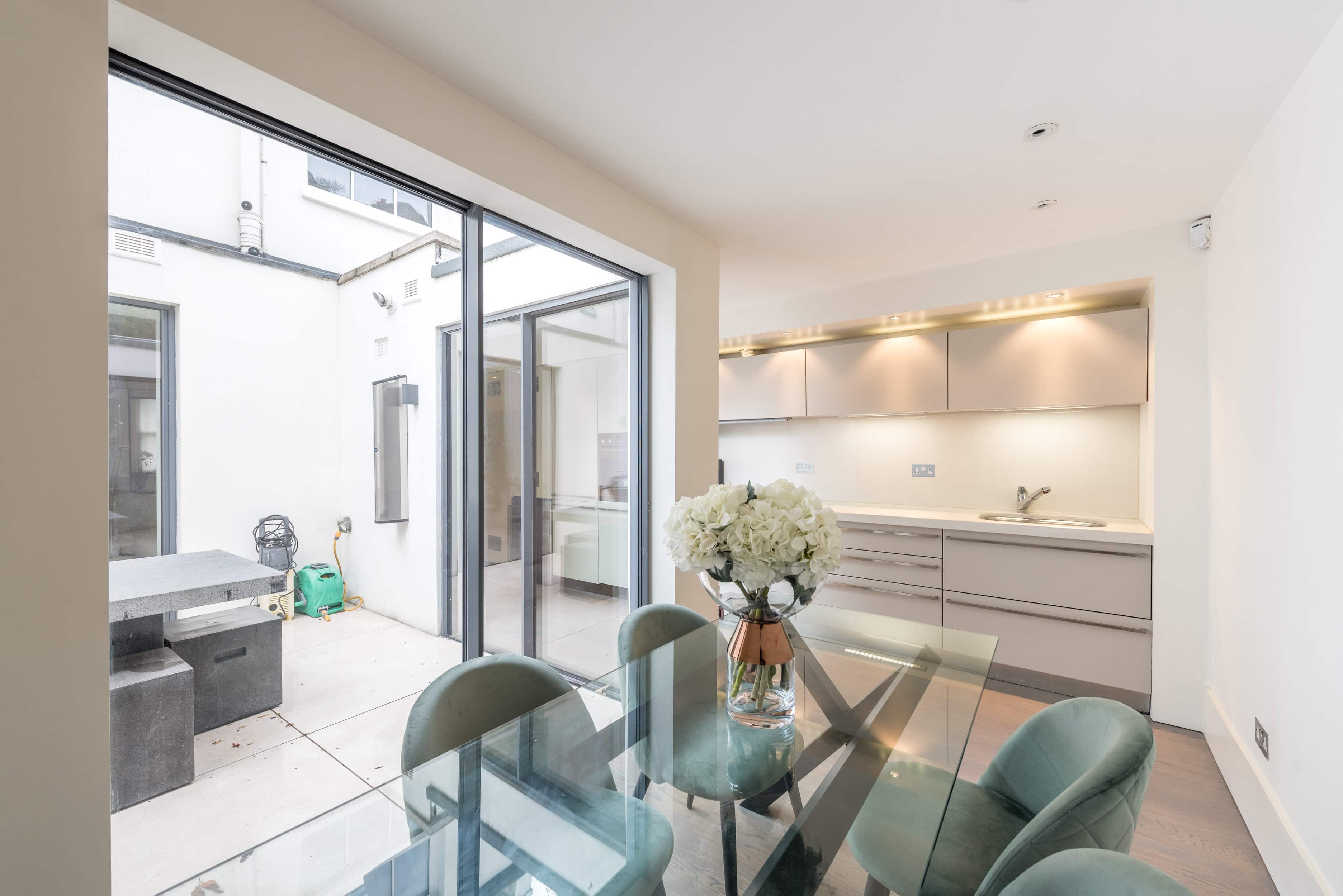 A dining room table and open plan kitchen with a patio in a house