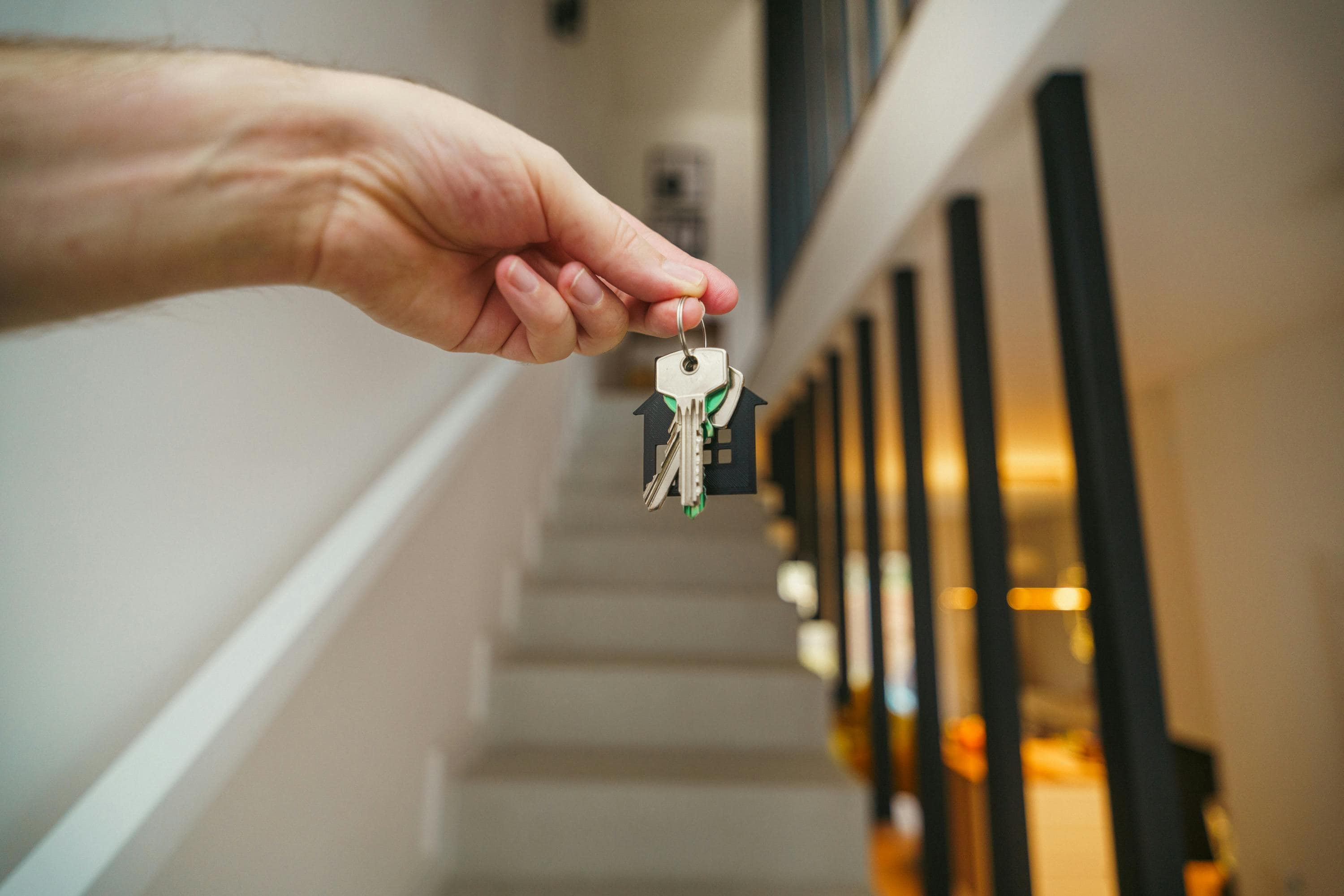 House Keys Being Held By A Staircase In A House