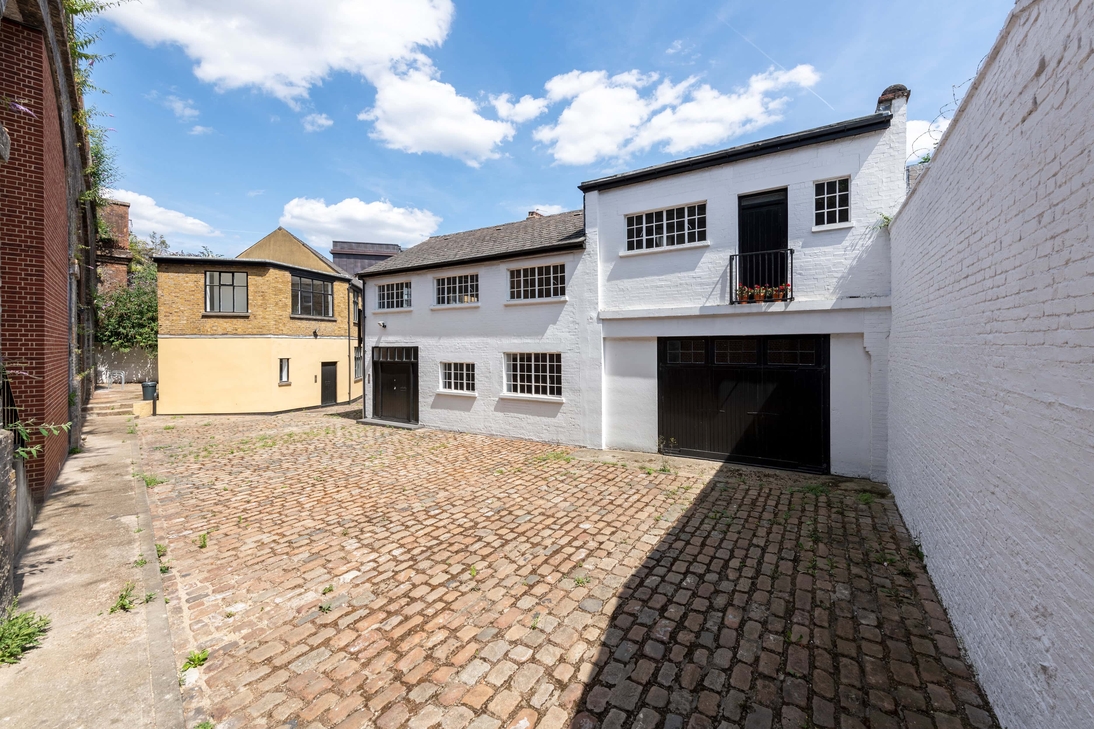 A white mews house with black shutters and a black garage door