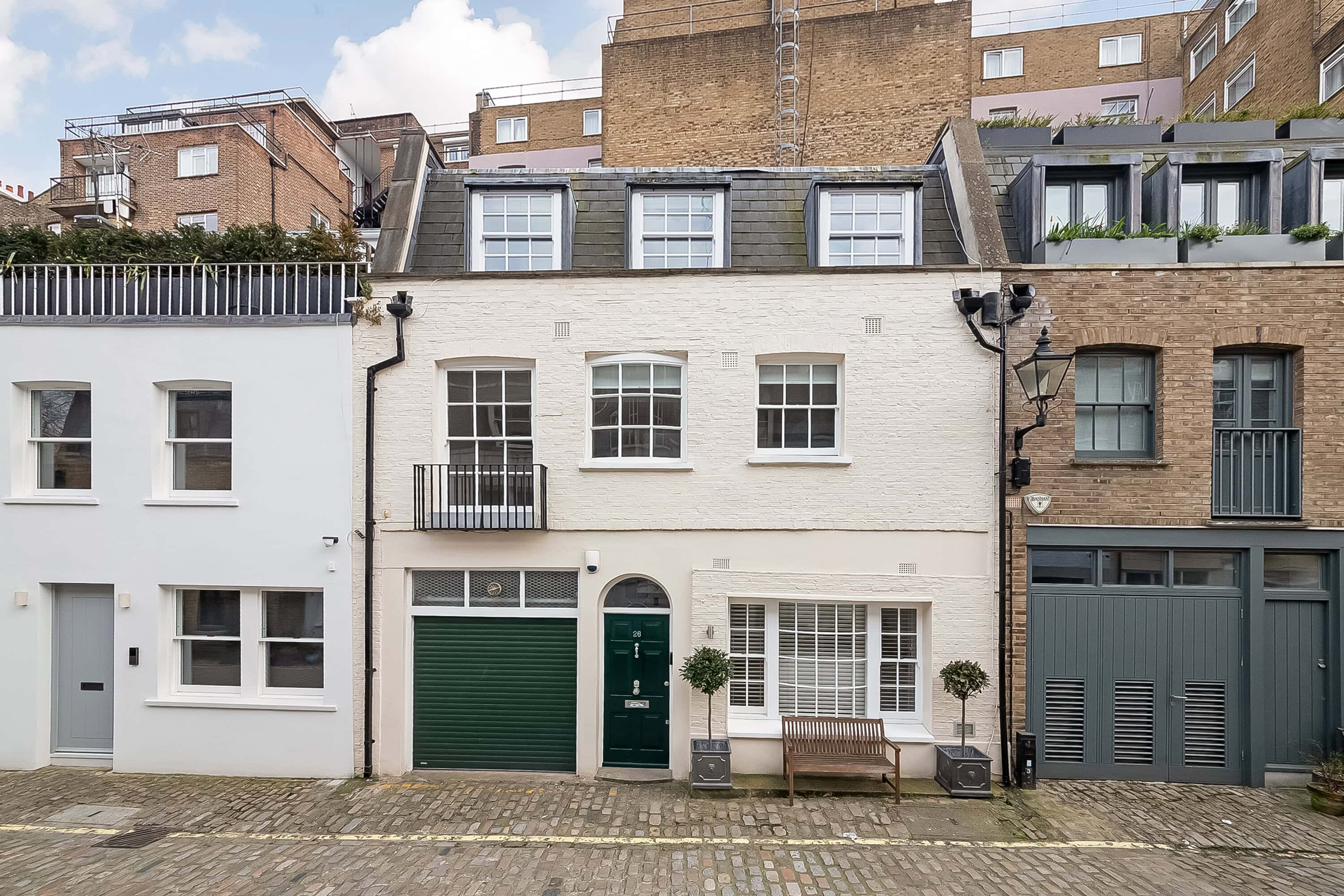 A cream mews property with a green front door