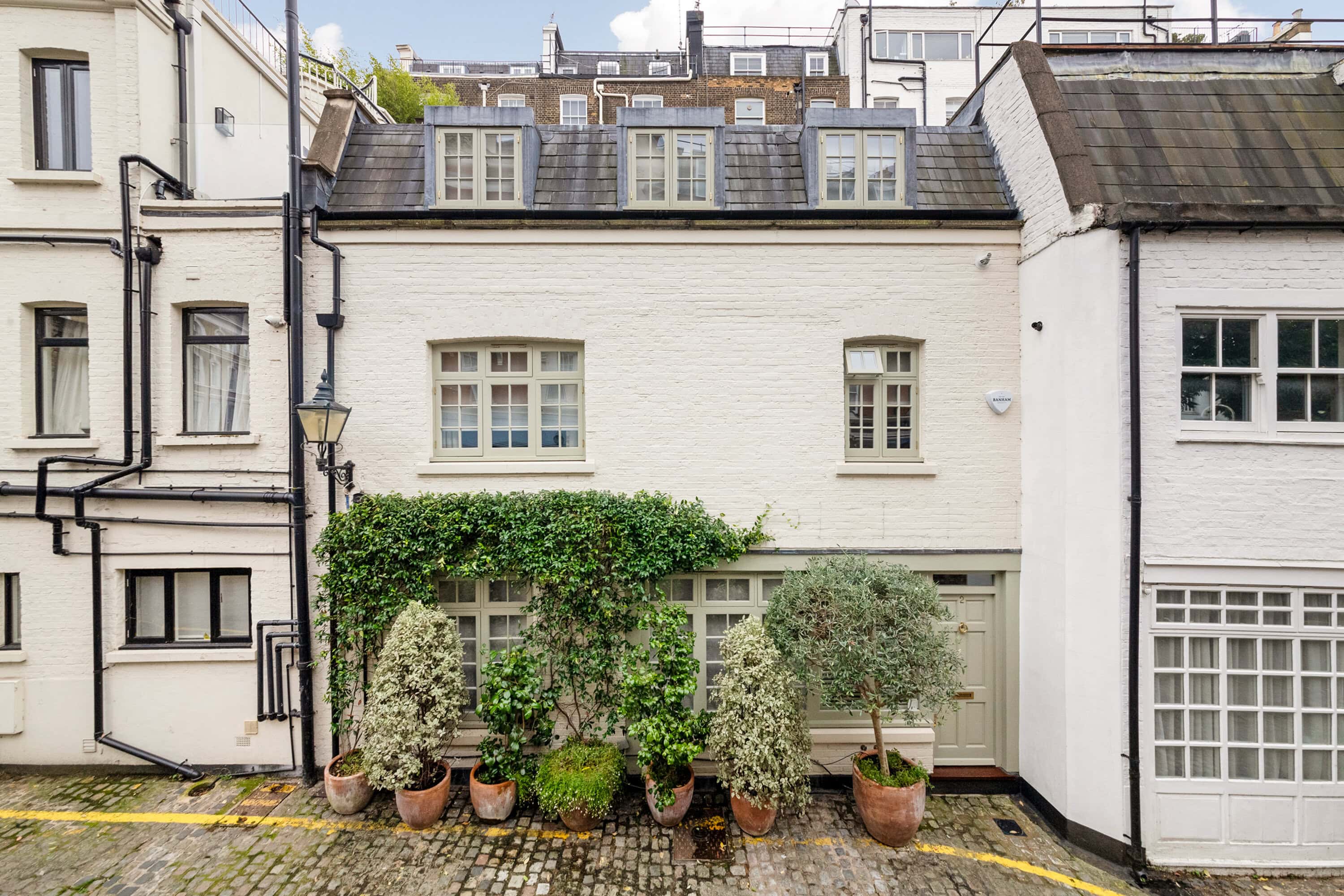 The exterior of a mews property with shrubbery and green plants outside the front door