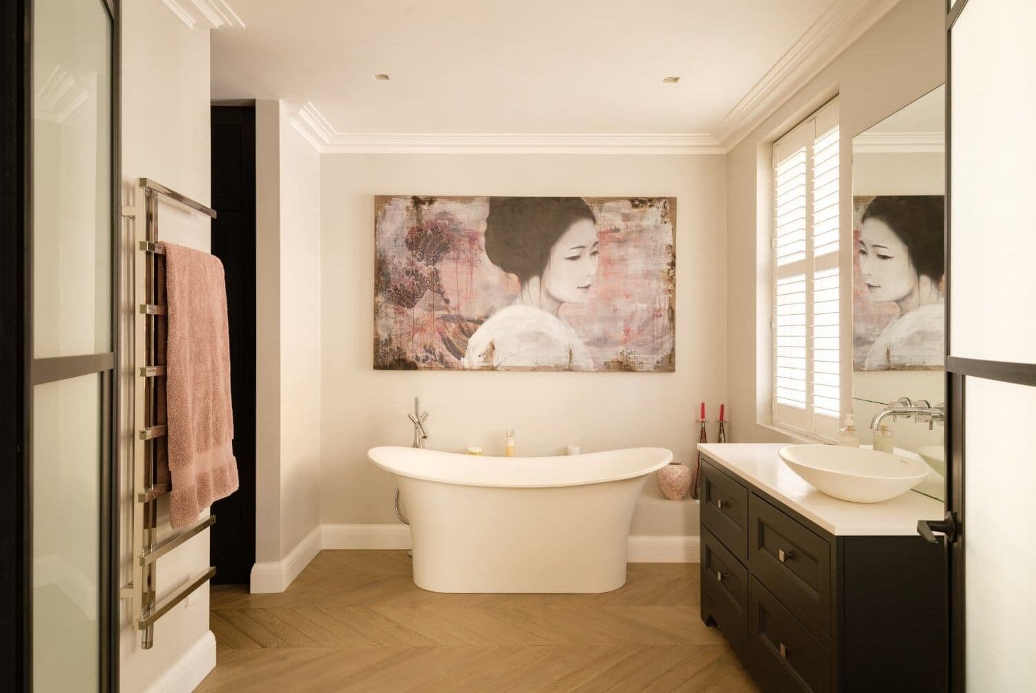 A bathtub in a bathroom with a painting on the wall