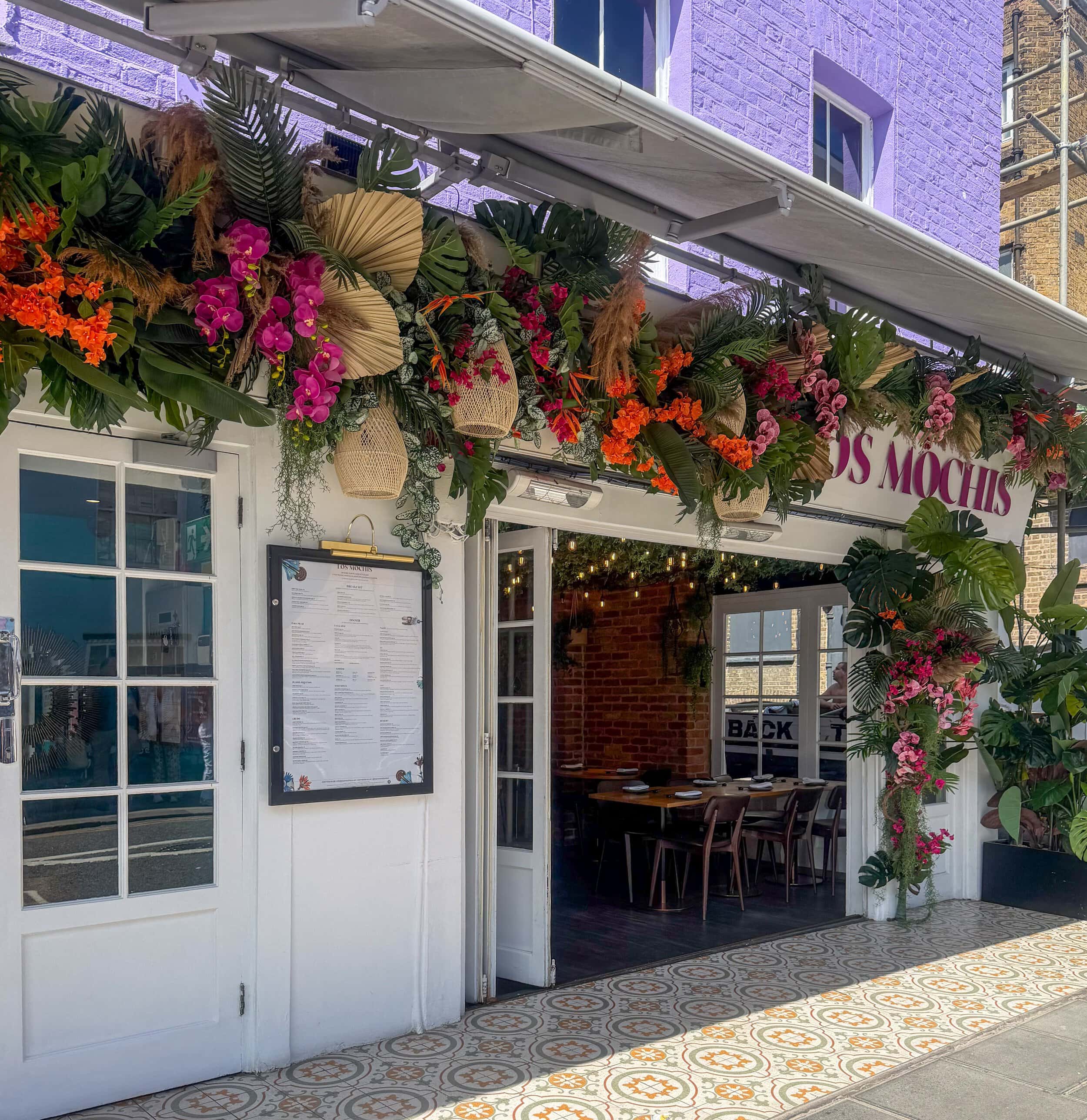 Charming restaurant entrance decorated with vibrant flowers in Notting Hill. This area is popular among foodies looking to buy in Notting HIll.