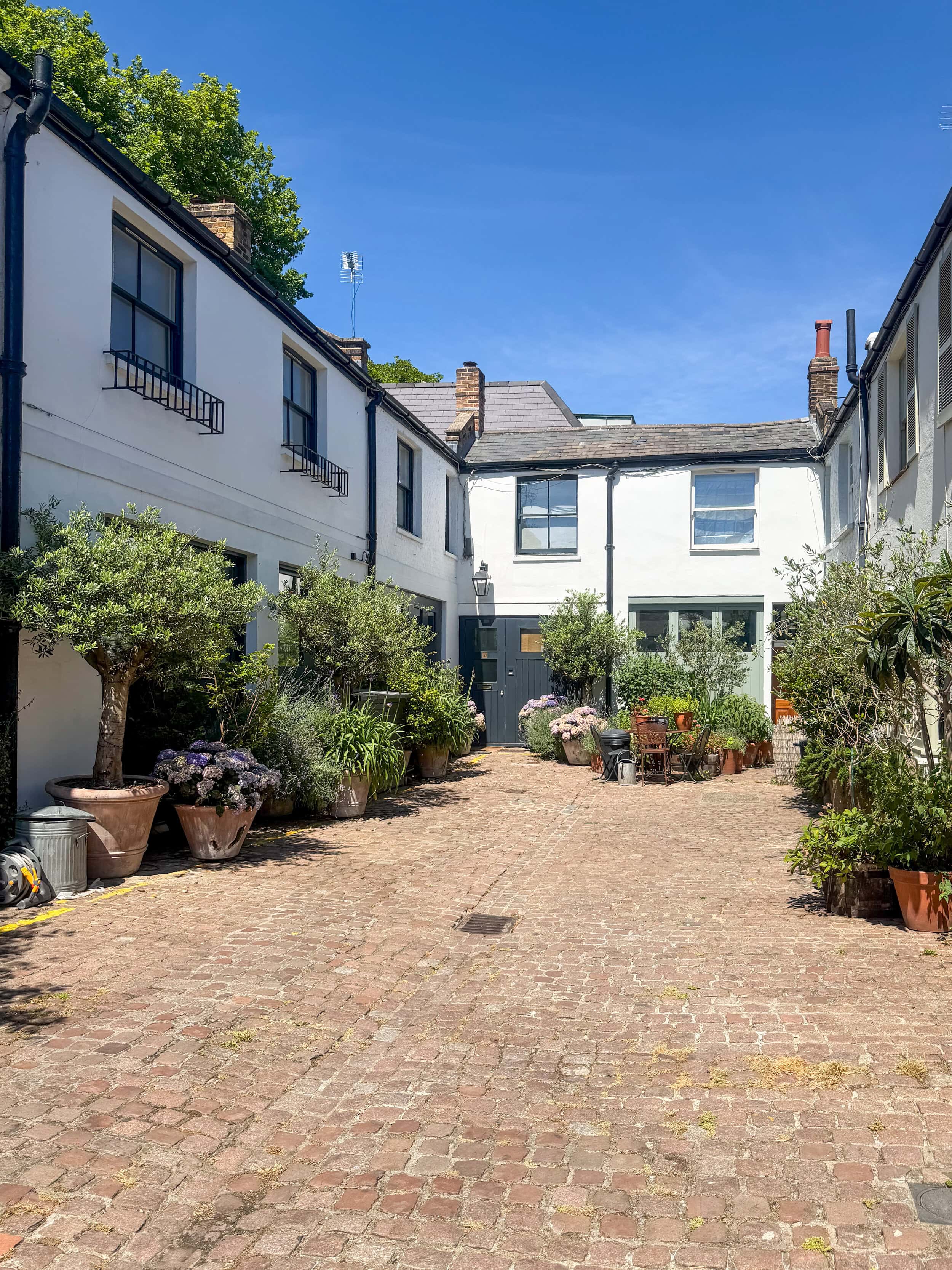 Beautiful courtyard in Notting Hill with potted plants and cobblestone paving, which is home to those who rent in Notting Hill