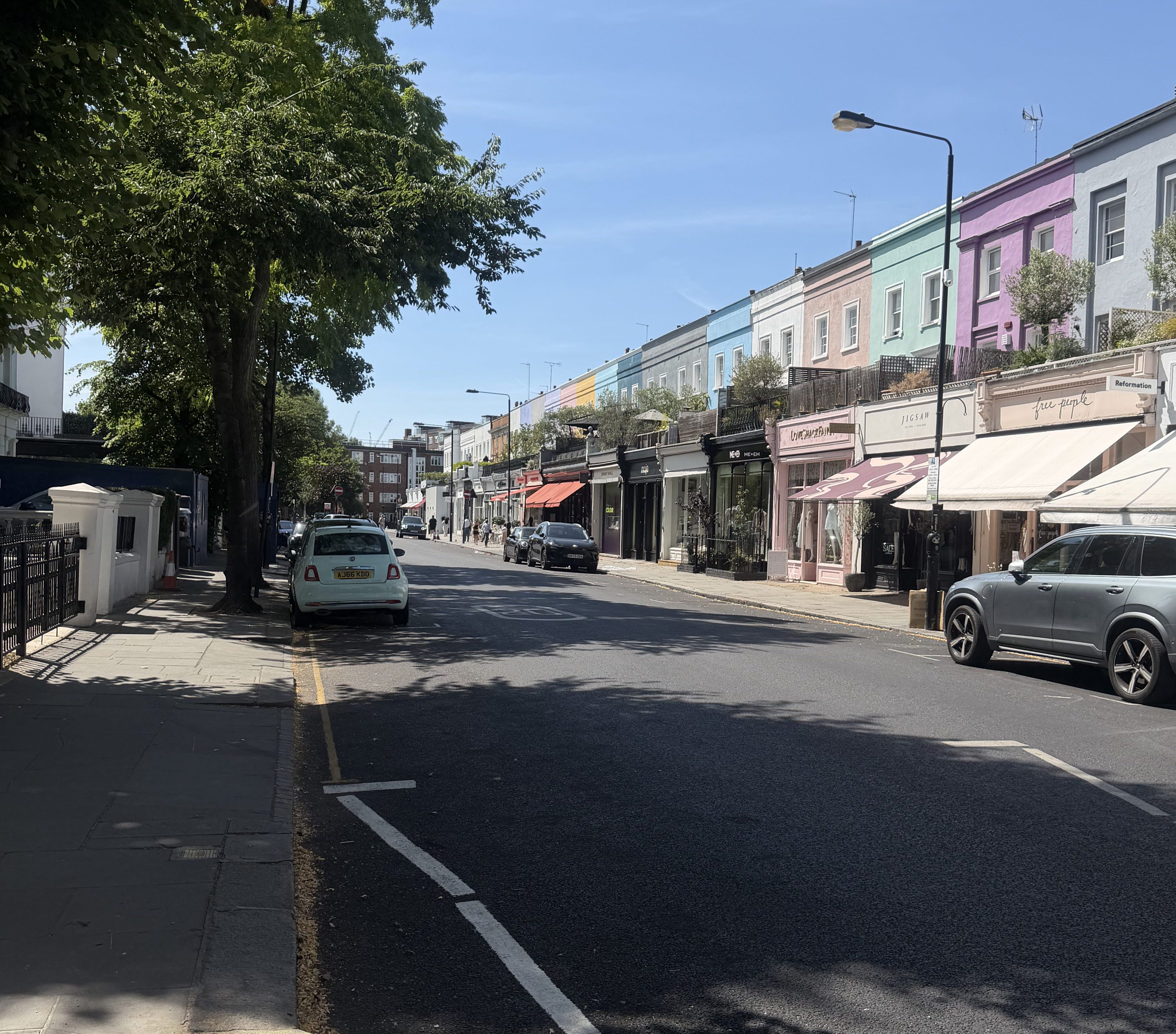 Vibrant pastel-coloured shops along a sunny street in Notting Hill.