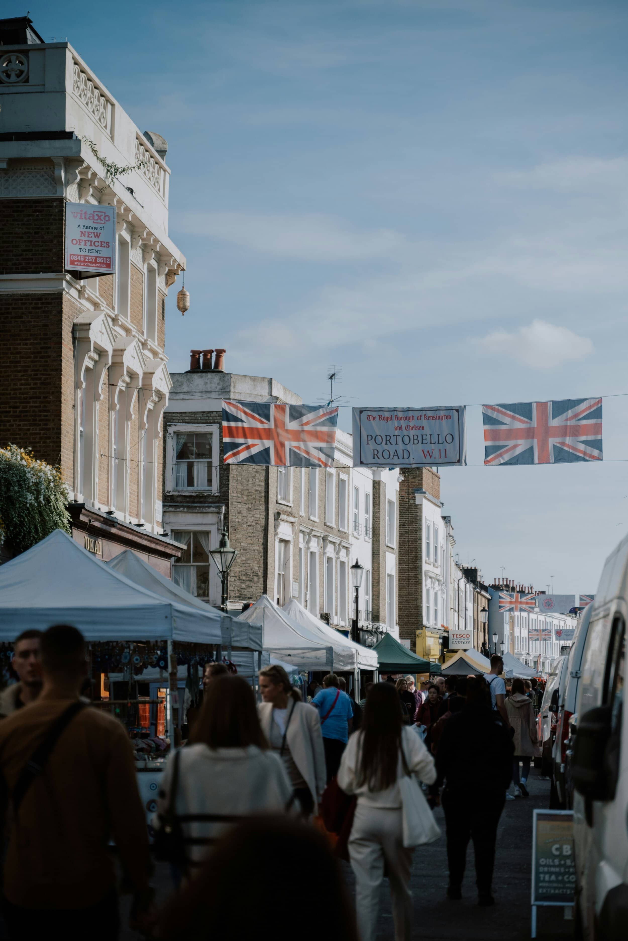 Vibrant street scene in Notting Hill with market stalls and shoppers some of who rent in Notting Hill